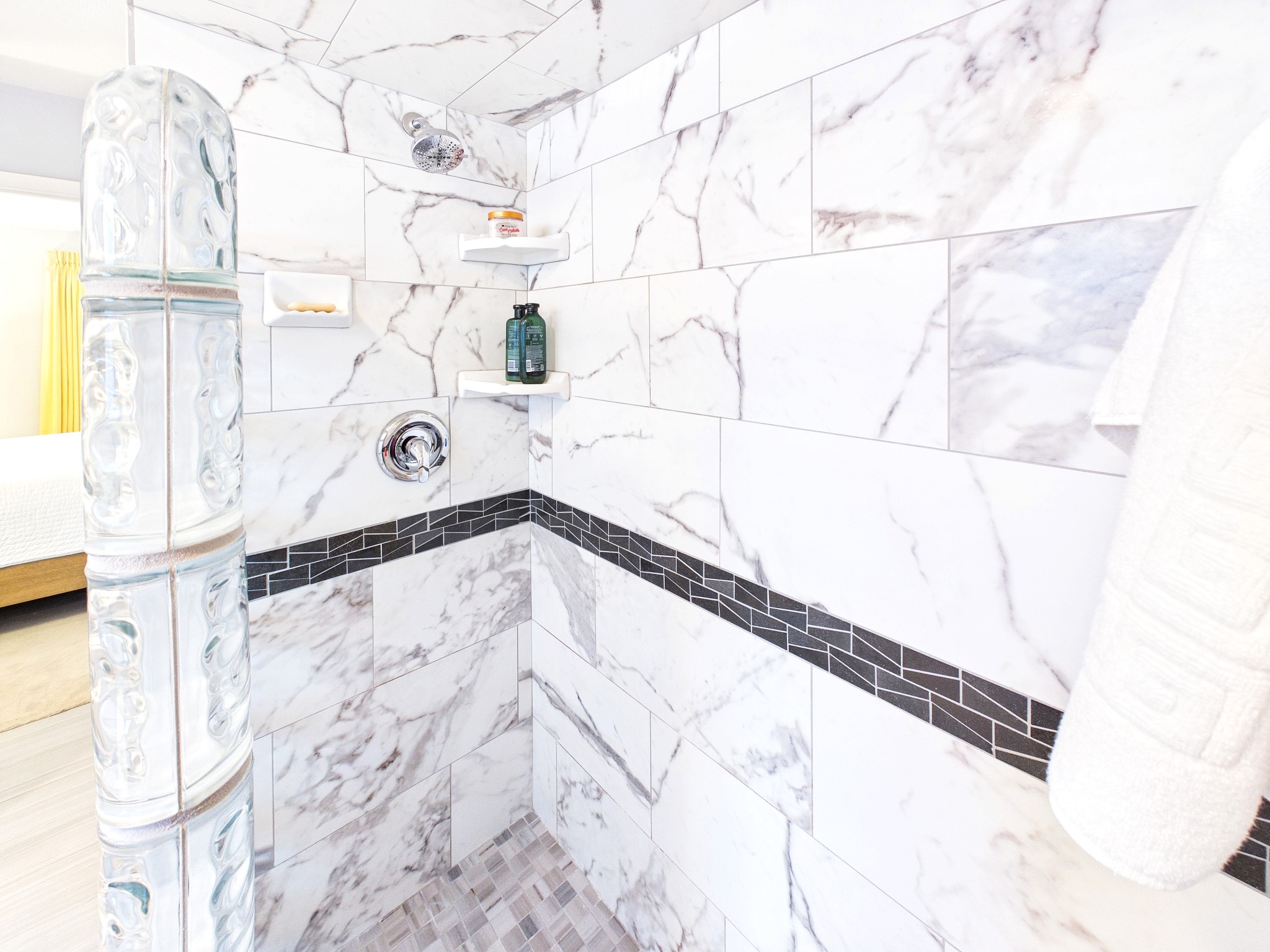 Indulge in the luxurious elegance of a primary shower adorned with sleek marble tiles and stylish accents, offering a serene escape.