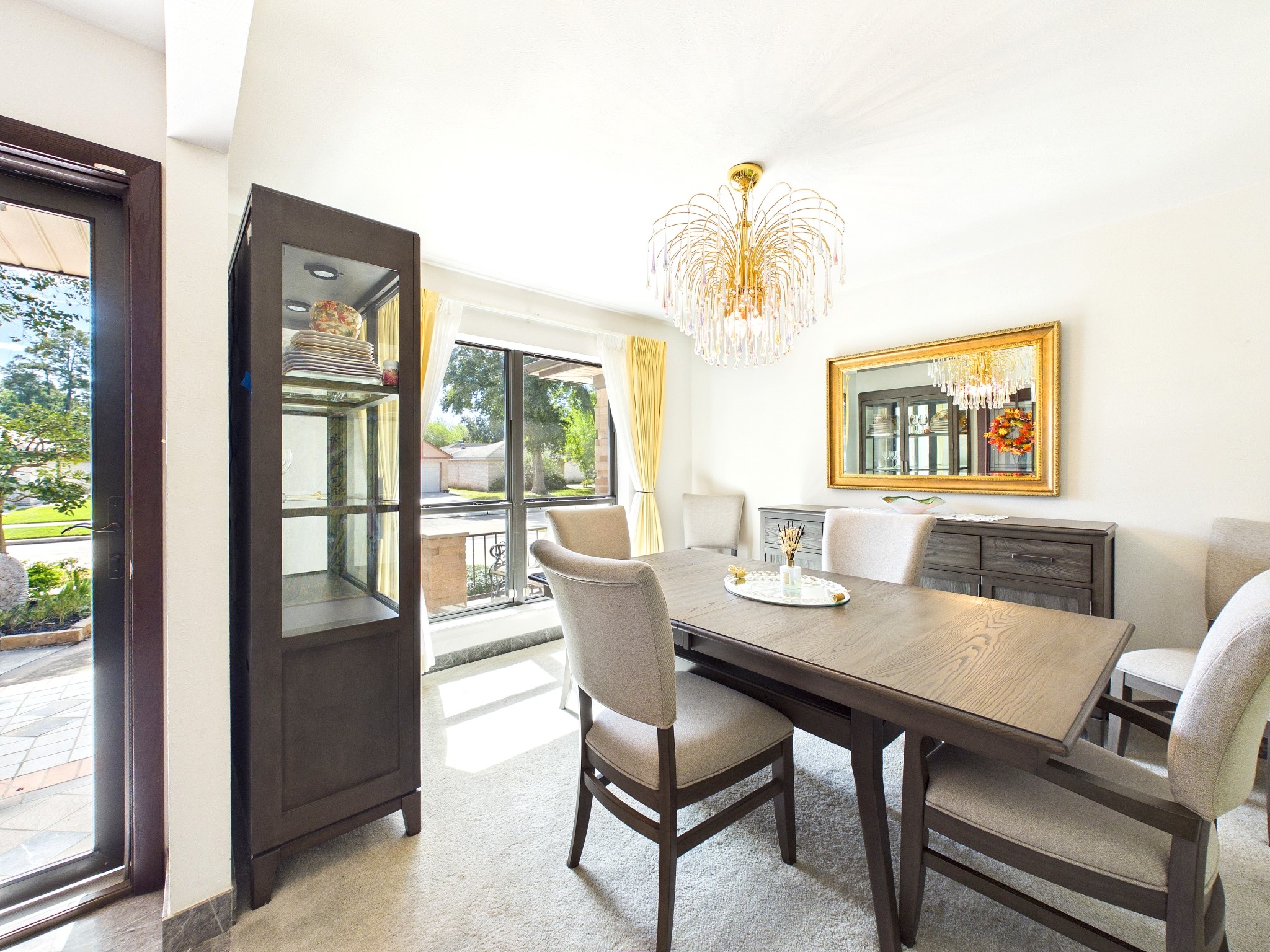 Elegant formal dining room bathed in natural light, featuring a striking chandelier and sophisticated furnishings, perfect for hosting memorable gatherings.