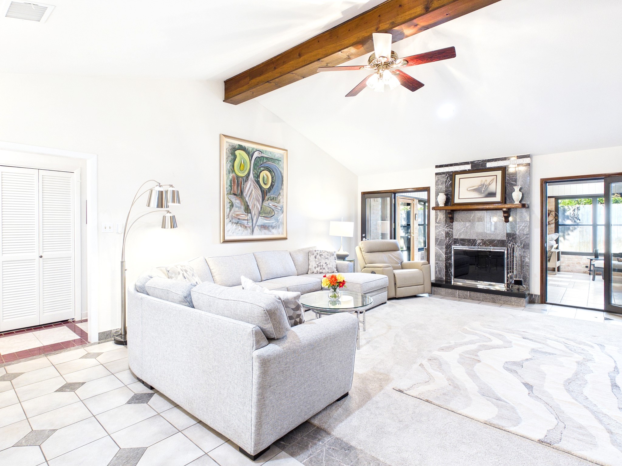 Experience the inviting charm of this open living area, featuring a cozy fireplace, elegant beams, and abundant natural light, perfect for relaxation and entertaining.