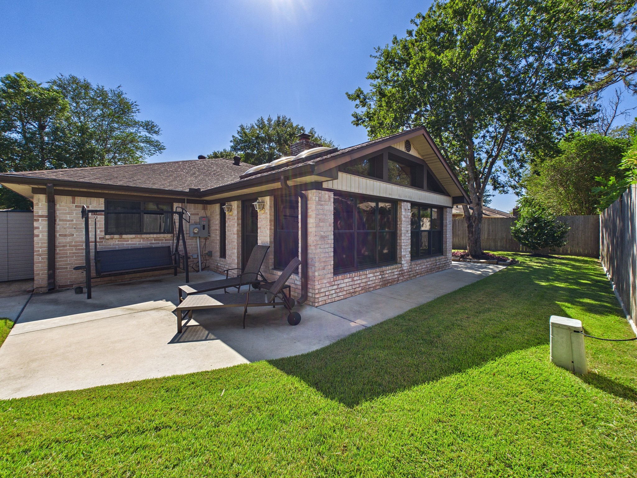 Charming backyard retreat with a spacious patio, perfect for relaxation and outdoor gatherings, surrounded by lush greenery and mature trees.