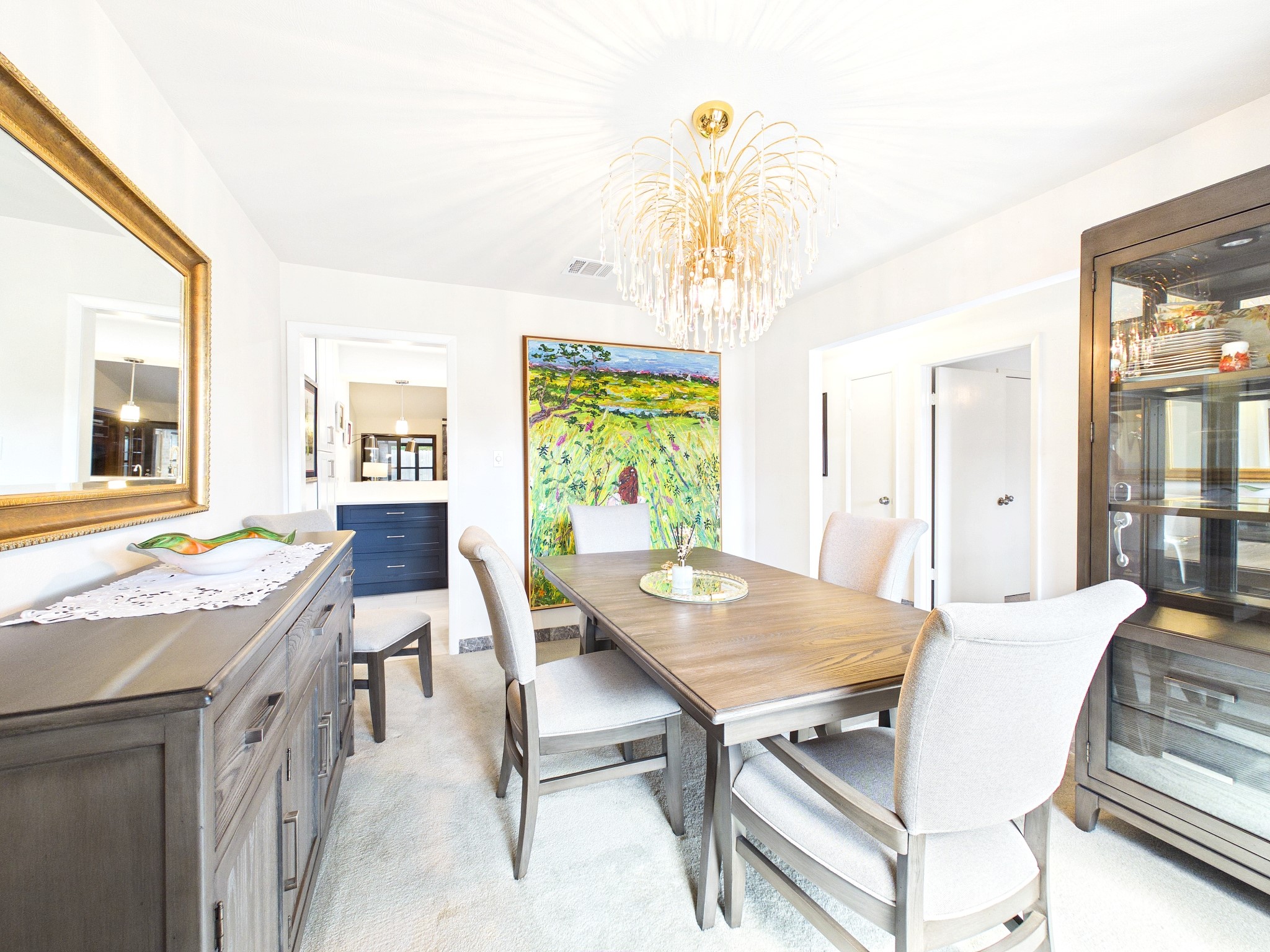 Elegant formal dining space featuring a sophisticated chandelier, plush seating, and a vibrant art piece, perfect for memorable gatherings.