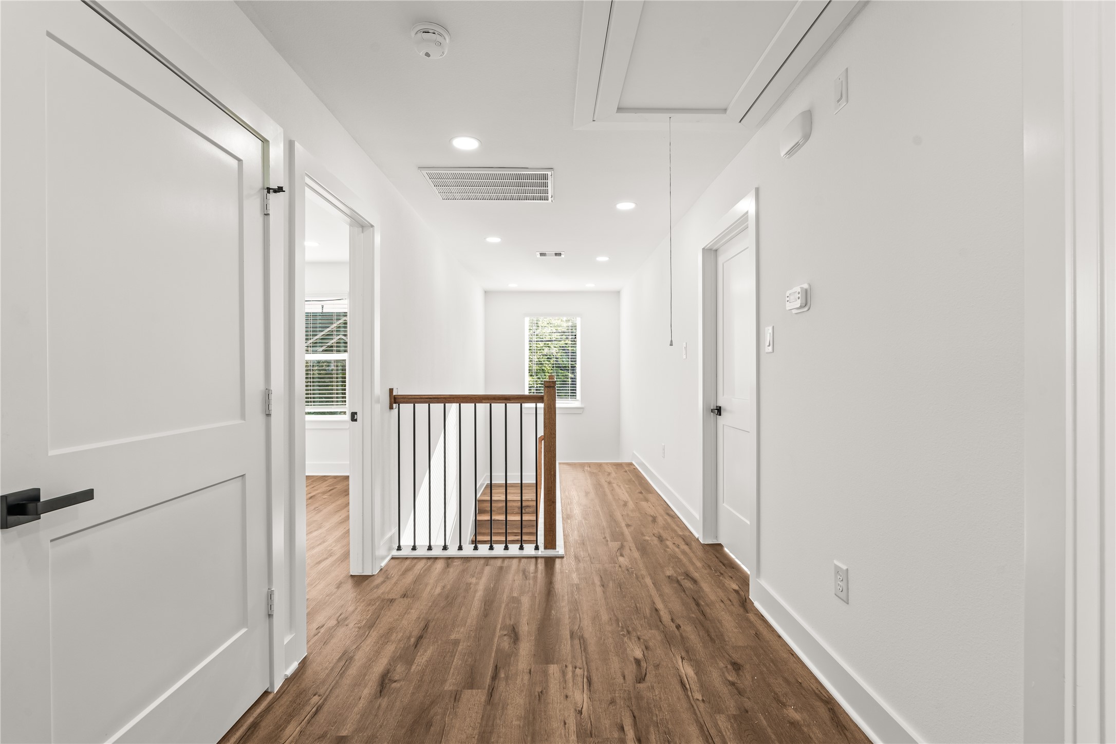 Thoughtful zoning. The upper level separates the bedrooms seamlessly with a clean, bright corridor anchored by beautiful iron spindle details.