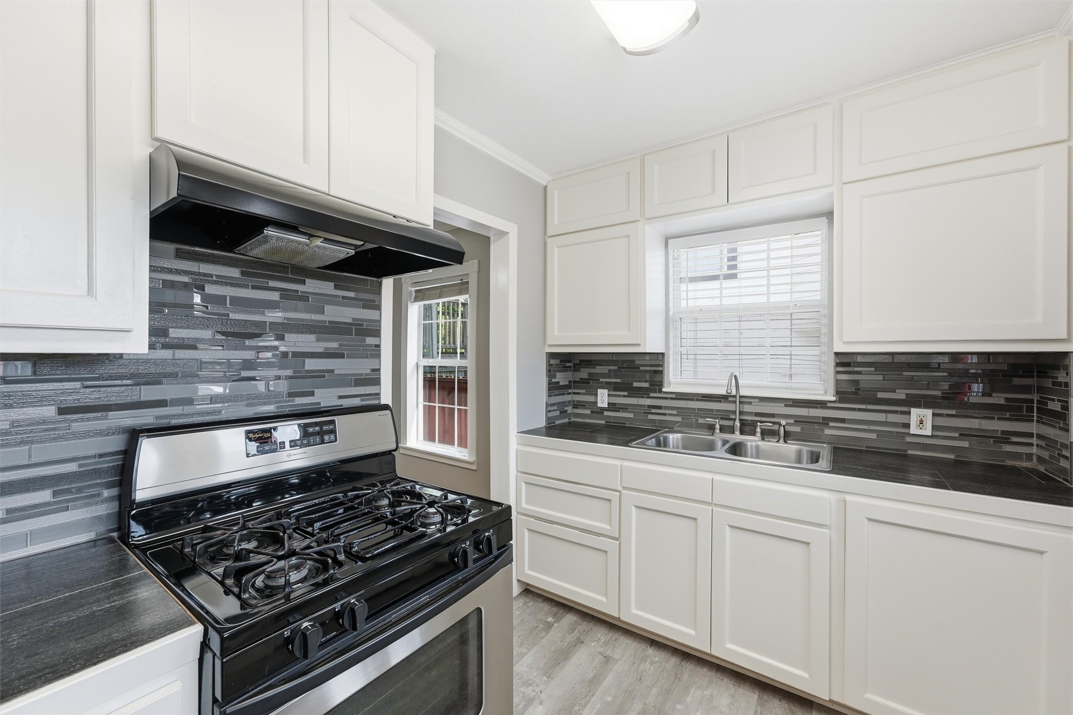 Kitchen features glass block backsplash and tile countertops.