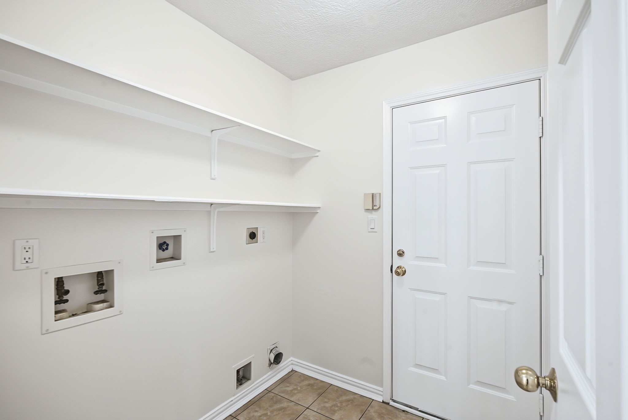 A dedicated laundry room includes washer and dryer connections, overhead shelving, and hanging space to simplify laundry day.