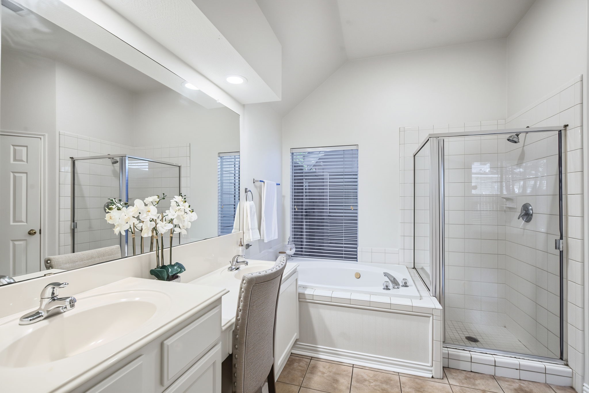 Dual sinks, a seated vanity area, a soaking tub, and a separate glass-enclosed shower give the primary bathroom a practical, spacious layout.