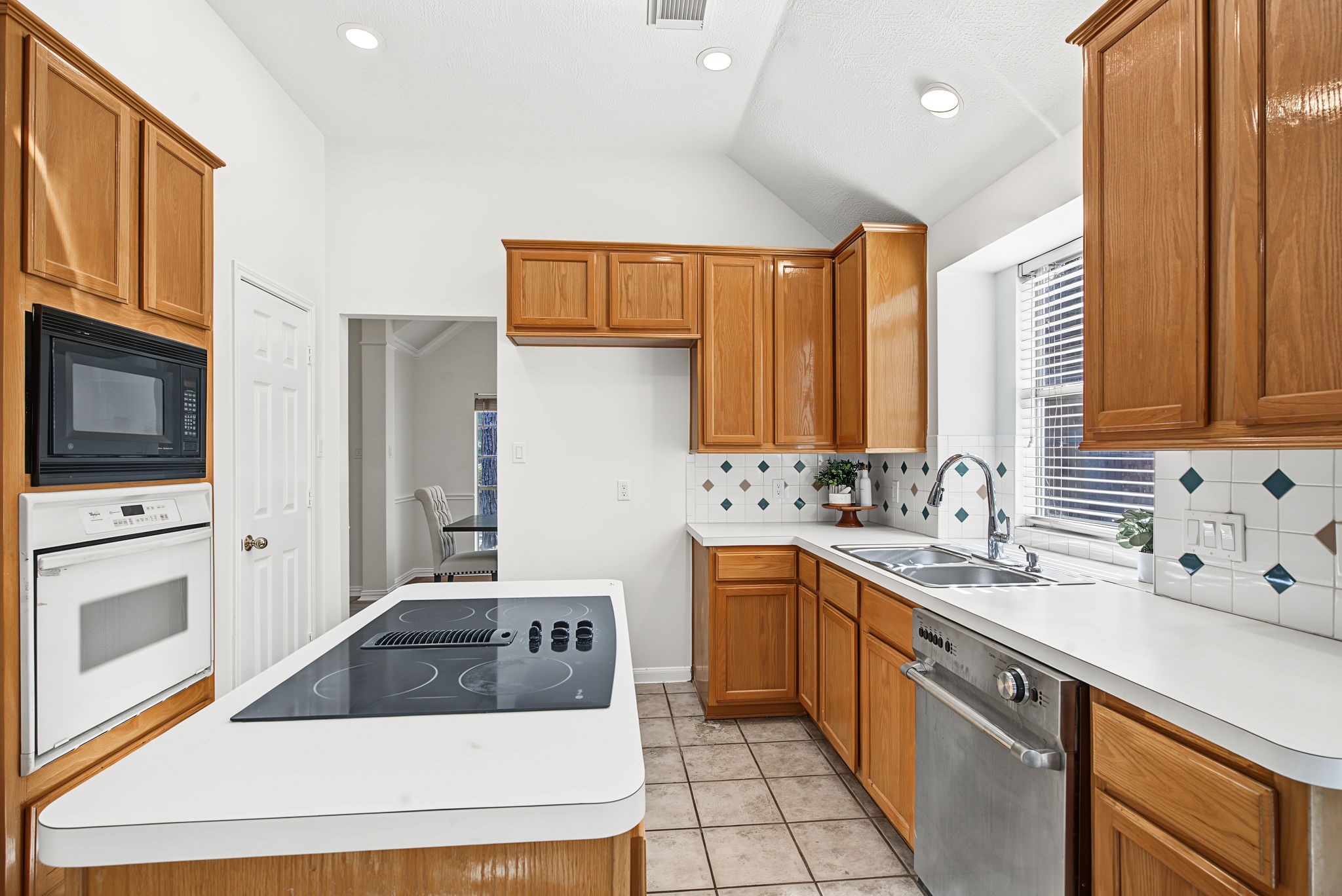 The island cooktop and built-in oven and microwave keep cooking functions organized, with surrounding cabinets providing plentiful storage.