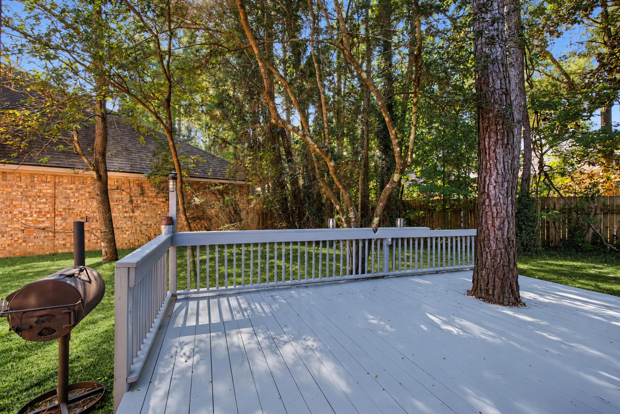 The freshly recoated rear deck extends your living space outdoors, with room to arrange seating beneath the mature trees.