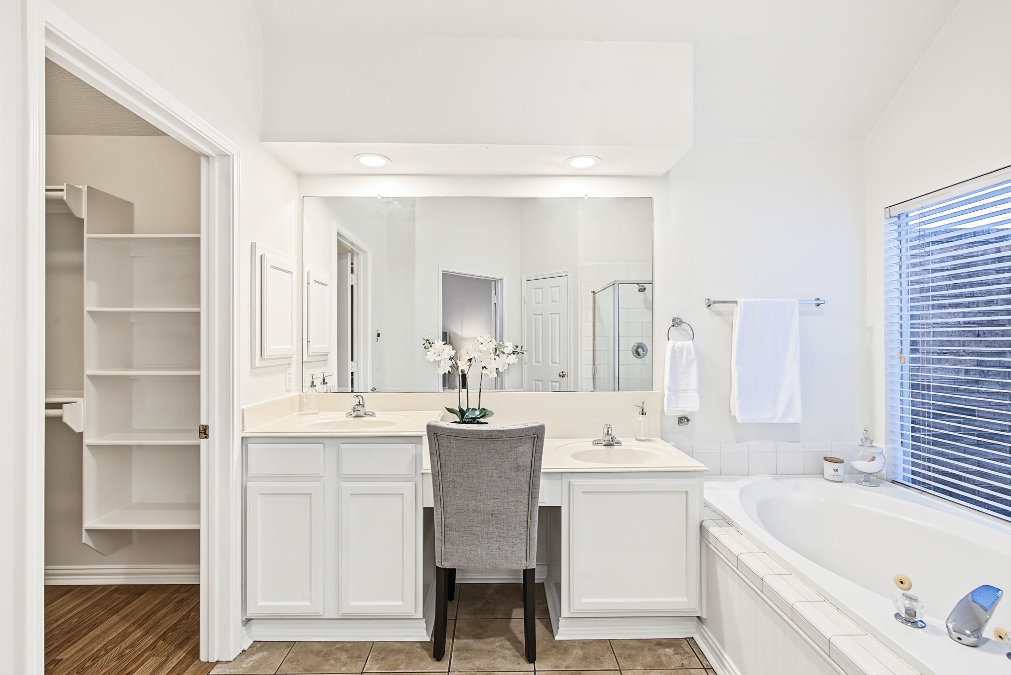 Built-in linen shelving, vanity storage, and a seated dressing area help keep the primary bathroom organized.