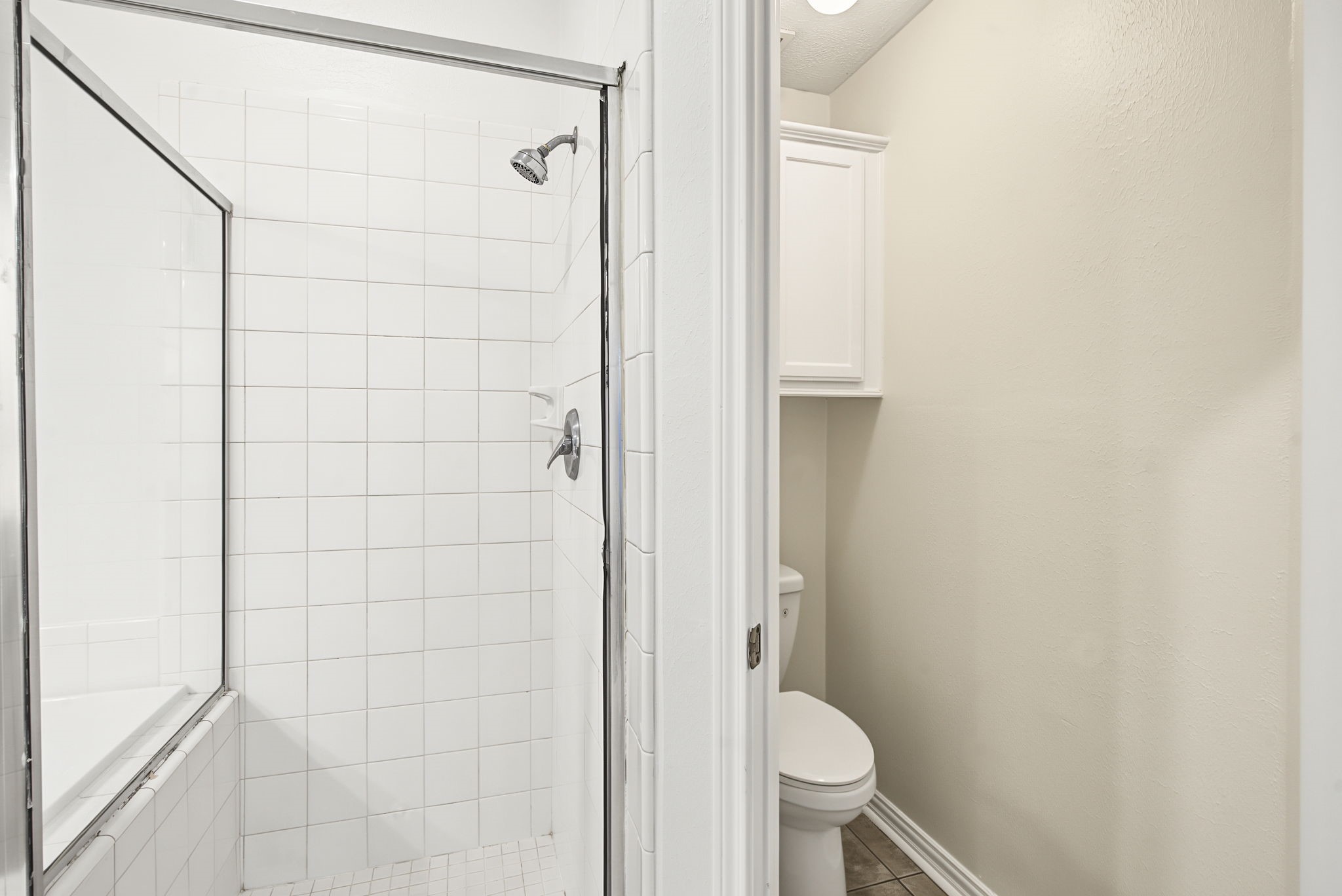 The primary bathroom includes a separate glass-enclosed tiled shower, giving you the convenience of both a shower and a tub.