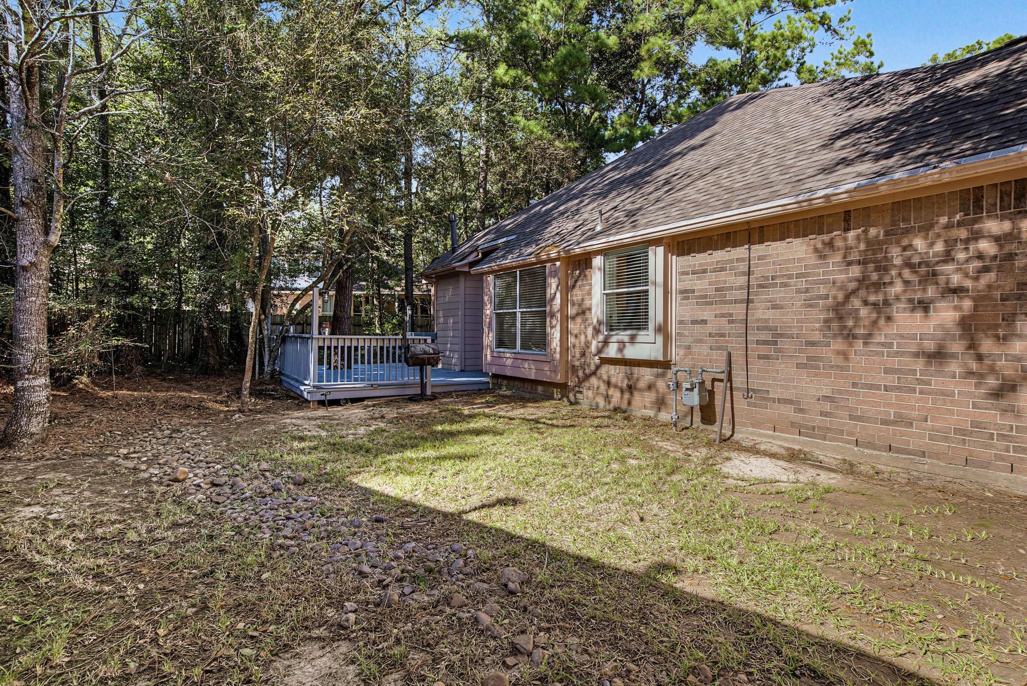 The side yard extends alongside the brick exterior and connects to the rear deck, providing another usable stretch of outdoor space.