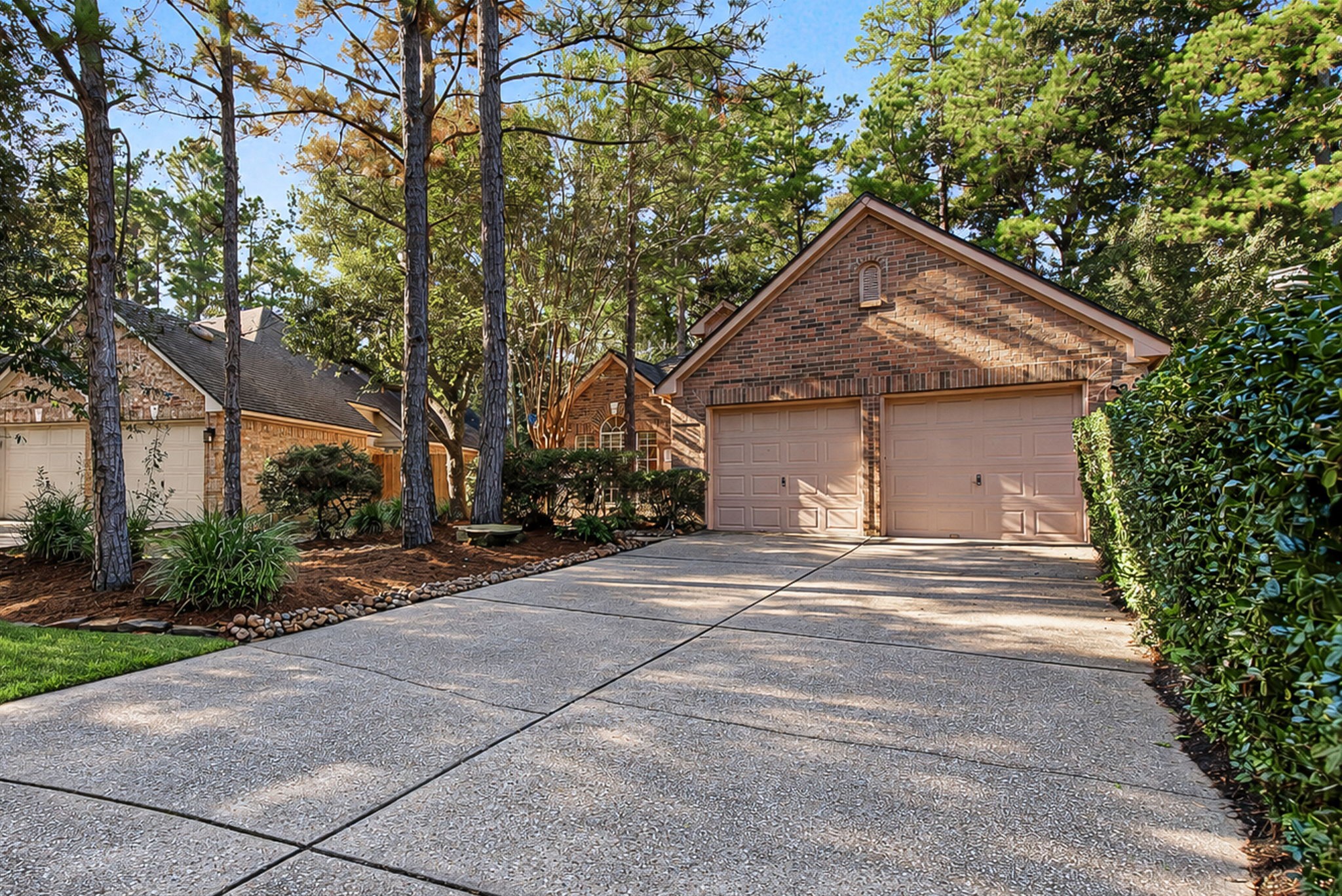 A broad double-wide driveway leads to the attached two-car garage, with mature landscaping adding character to the approach.