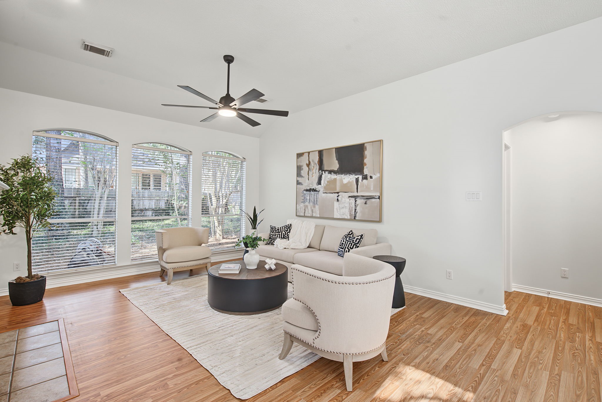 An open living area offers flexibility for your furniture arrangement, with tall windows drawing the eye toward the wooded backyard.