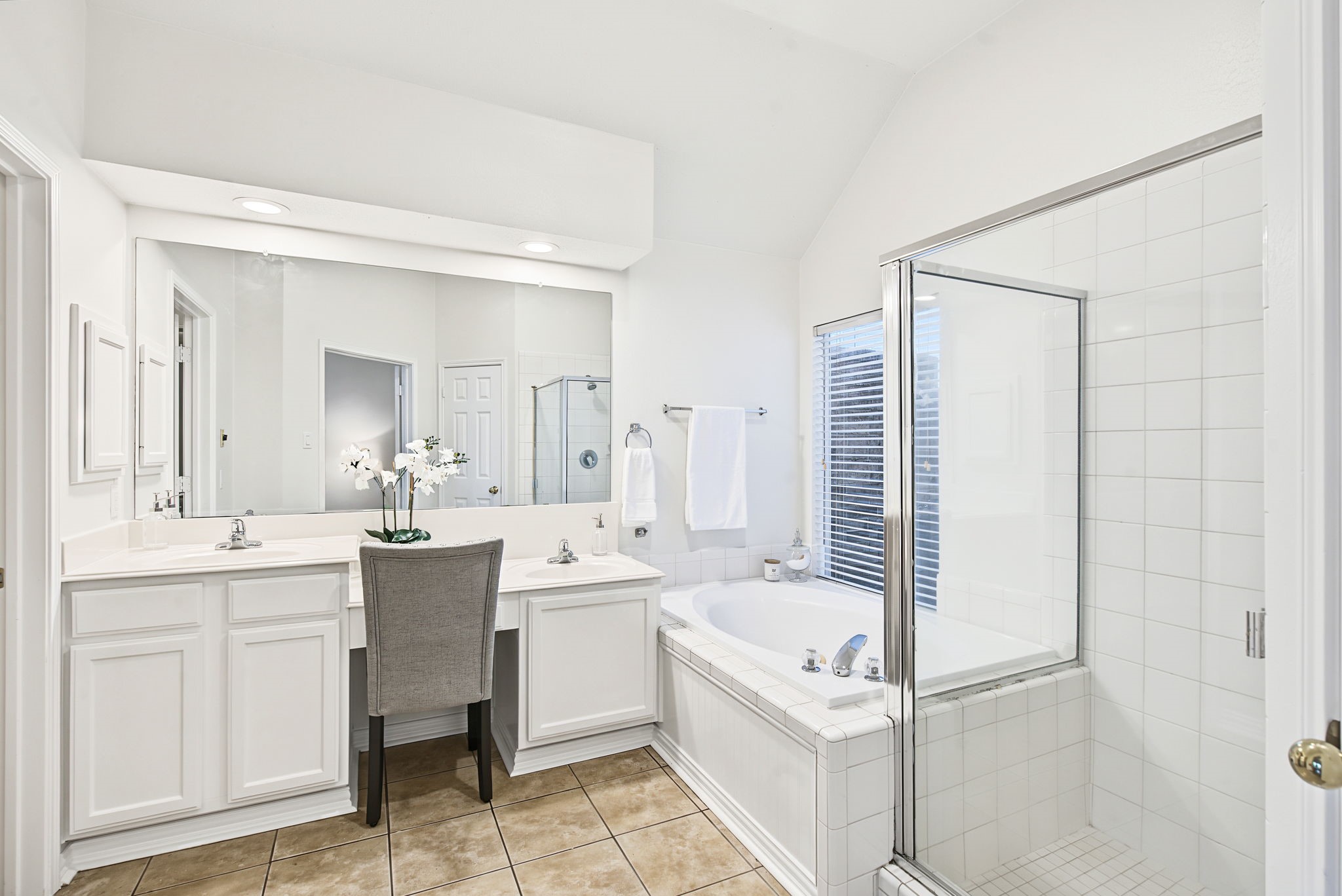 A wide mirror and dual-sink vanity complement the primary bathrooms separate tub and shower, offering room to personalize the finishes over time.