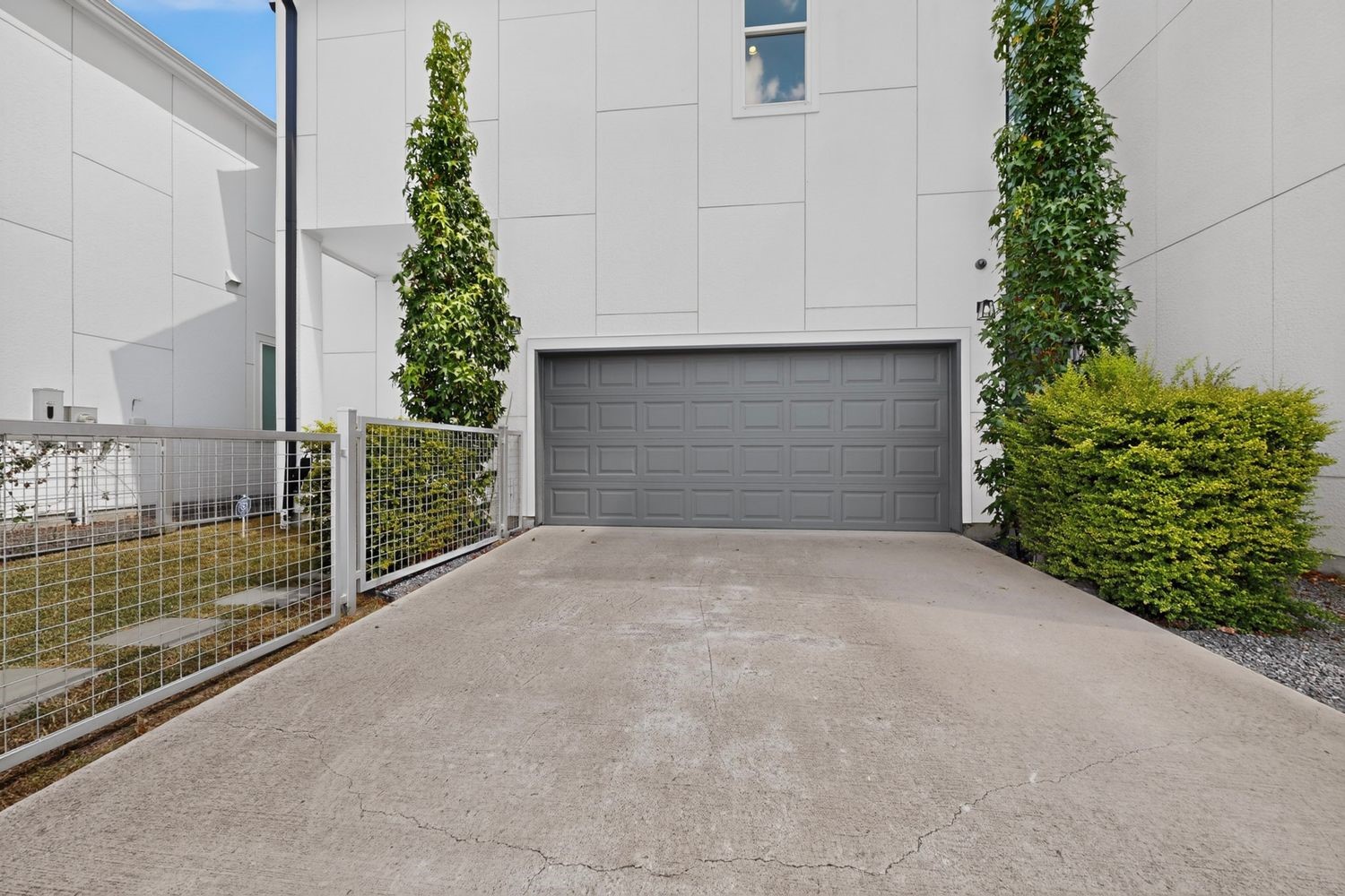 And from the rear you have your Two-car garage framed by lush greenery and your private double wide driveway, offering a clean and easy and contemporary entrance.