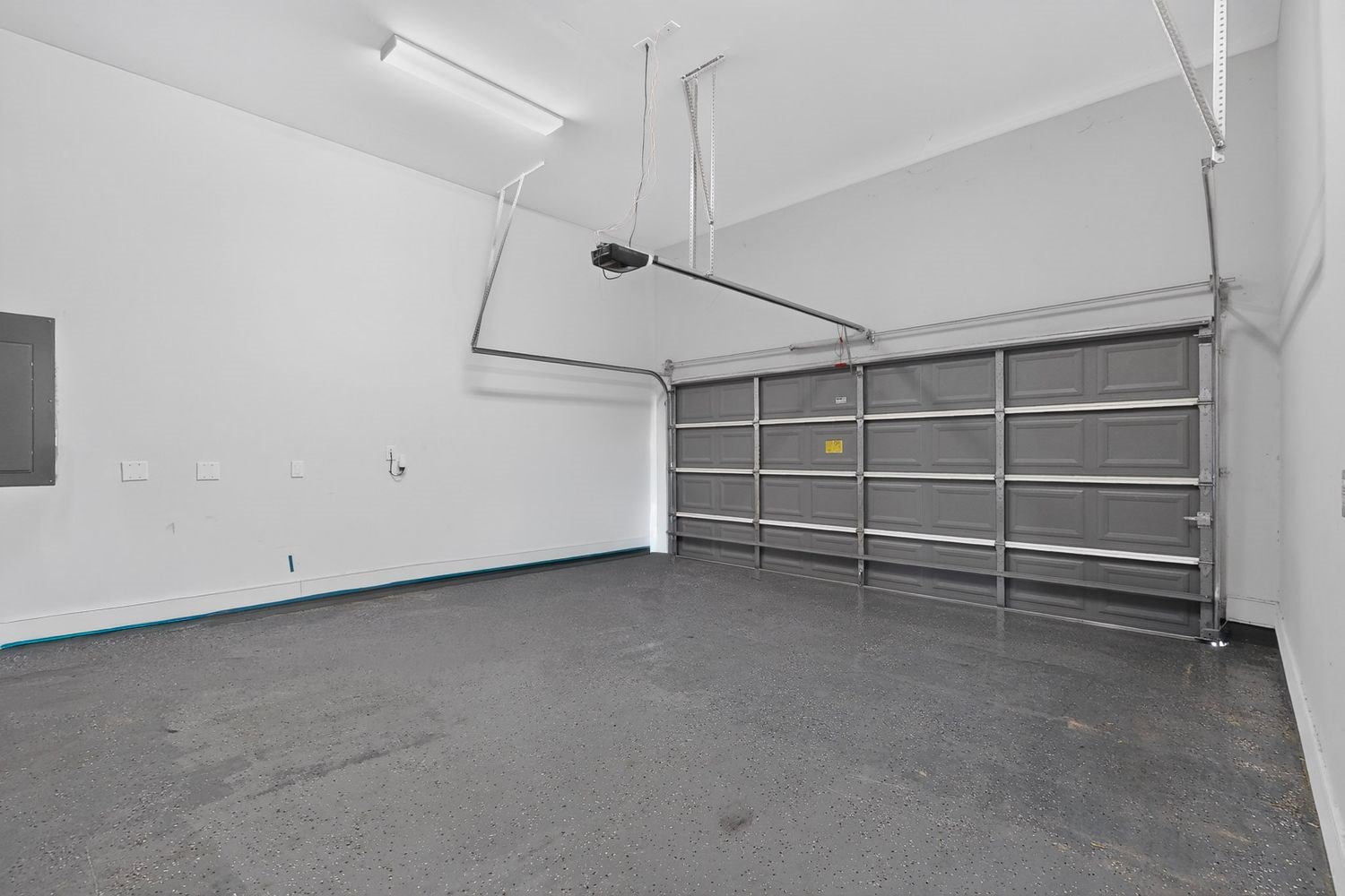 Spacious garage with a sleek, durable epoxy floor and ample overhead lighting, perfect for storage or projects.