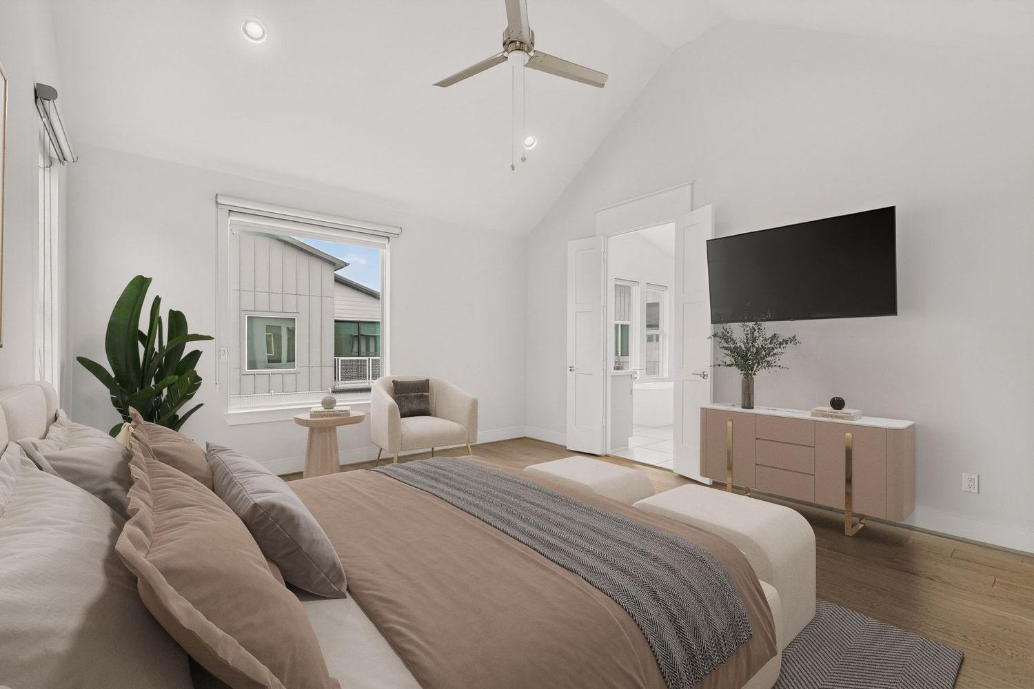 Another look a the modern comfort in this bright, spacious Primary bedroom featuring vaulted ceilings, elegant hardwood floors, and a sleek ceiling fan.