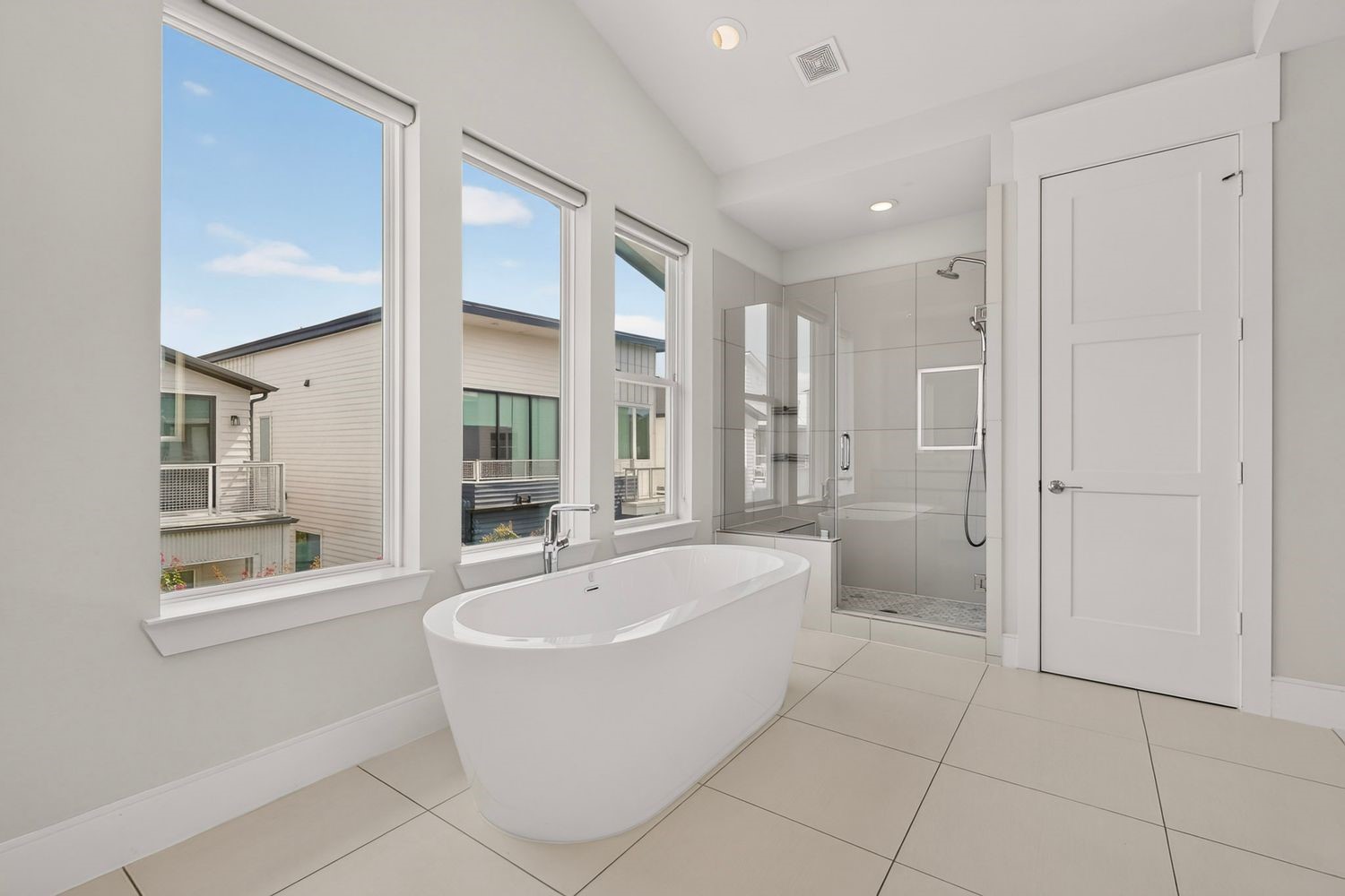 Luxurious bathroom featuring a freestanding soaking tub, large walk-in shower, and abundant natural light from multiple windows.