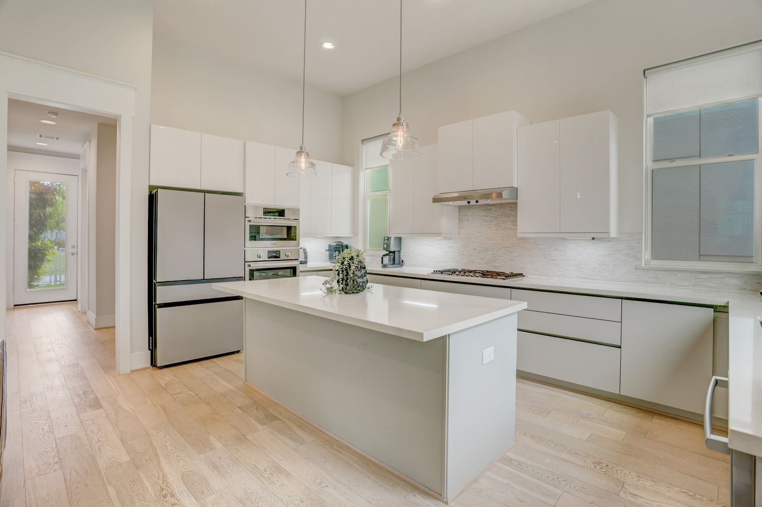 Sleek, modern kitchen featuring an island with pendant lighting, A five door LG refrigerator, stainless steel appliances, and ample cabinetry, all set on elegant hardwood floors.