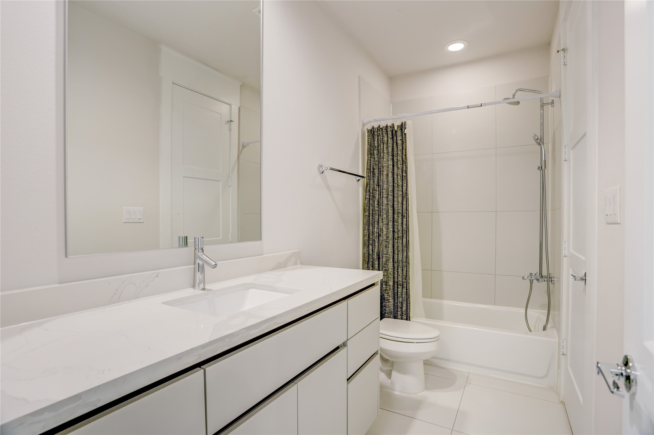 Sleek modern bathroom with a spacious vanity, elegant white countertop, and a combination shower and bathtub.