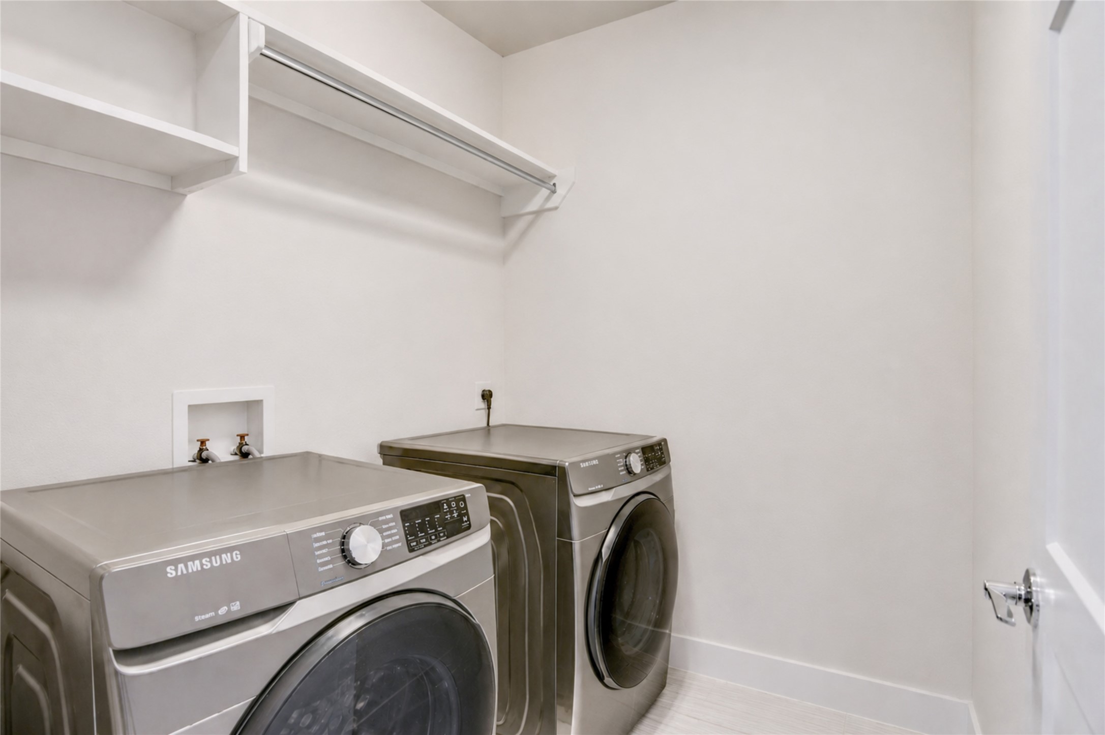 Spacious laundry room featuring modern appliances, ample shelving, and a sleek, clean design.