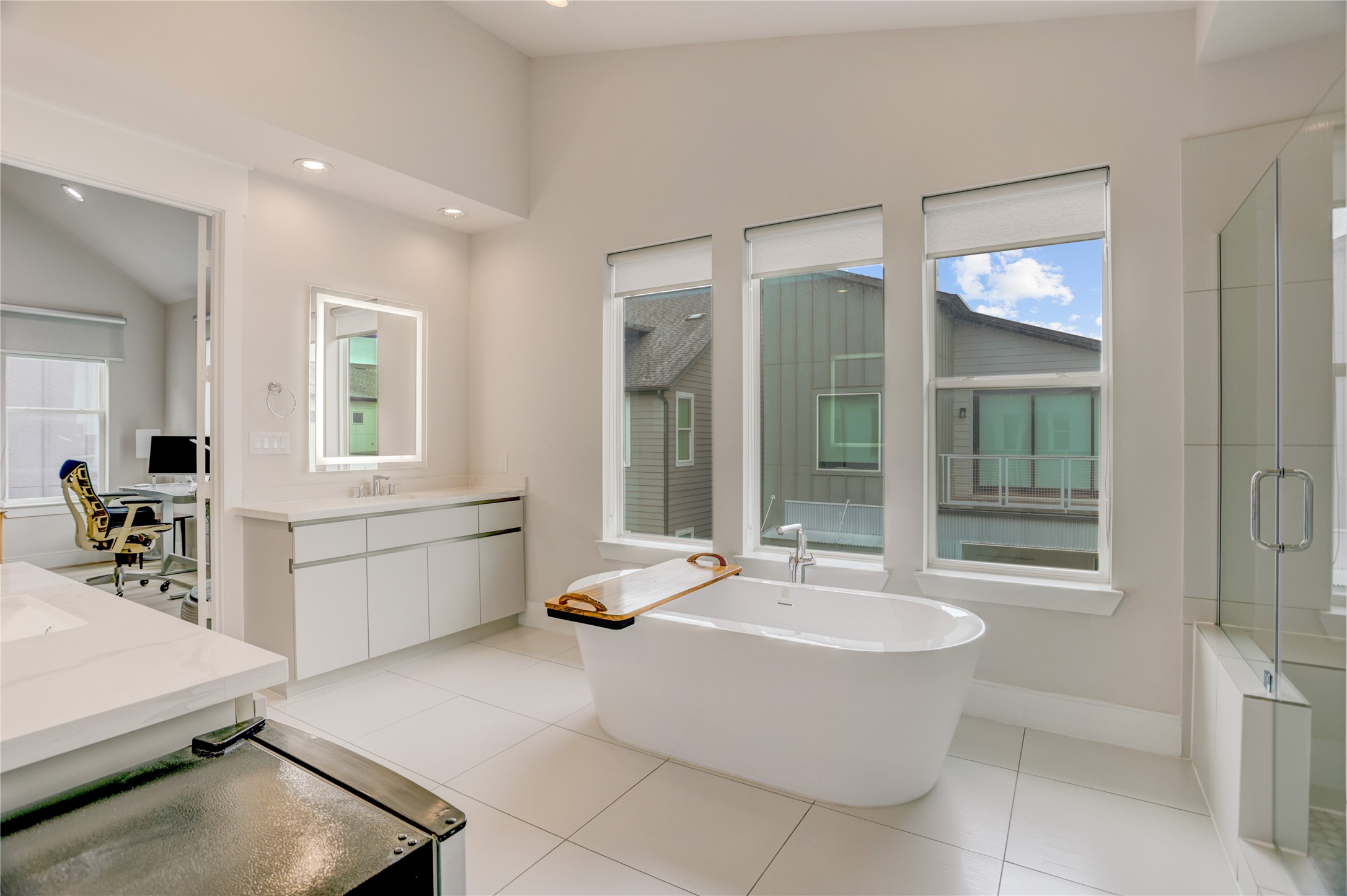 Spacious, modern bathroom features a luxurious freestanding tub, large windows for natural light, and sleek vanities, creating a serene retreat.