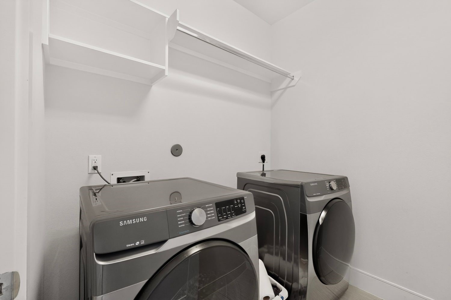 Modern laundry room featuring sleek Samsung washer and dryer, complemented by ample shelving for storage.