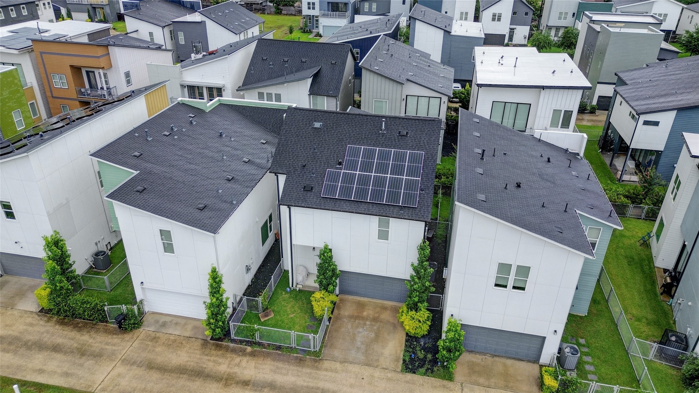 Modern cluster of contemporary homes featuring sleek designs and solar panels, offering sustainable living in a vibrant community.