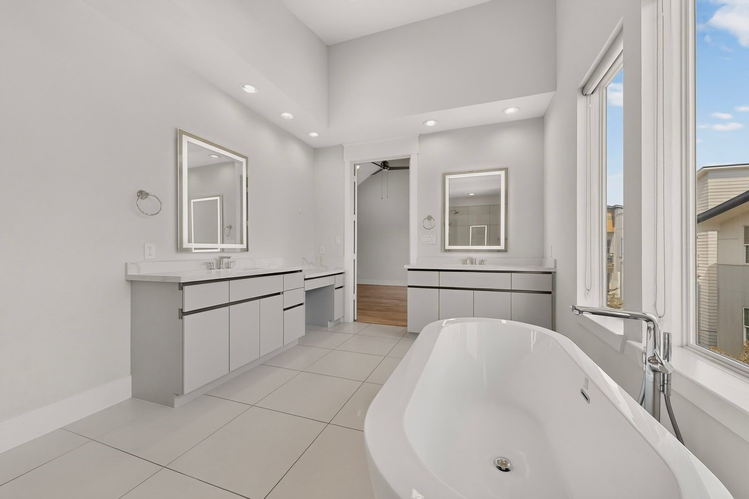 Spacious and modern bathroom featuring dual vanities, sleek cabinetry, and a luxurious freestanding tub set against awesome windows for abundant natural light.