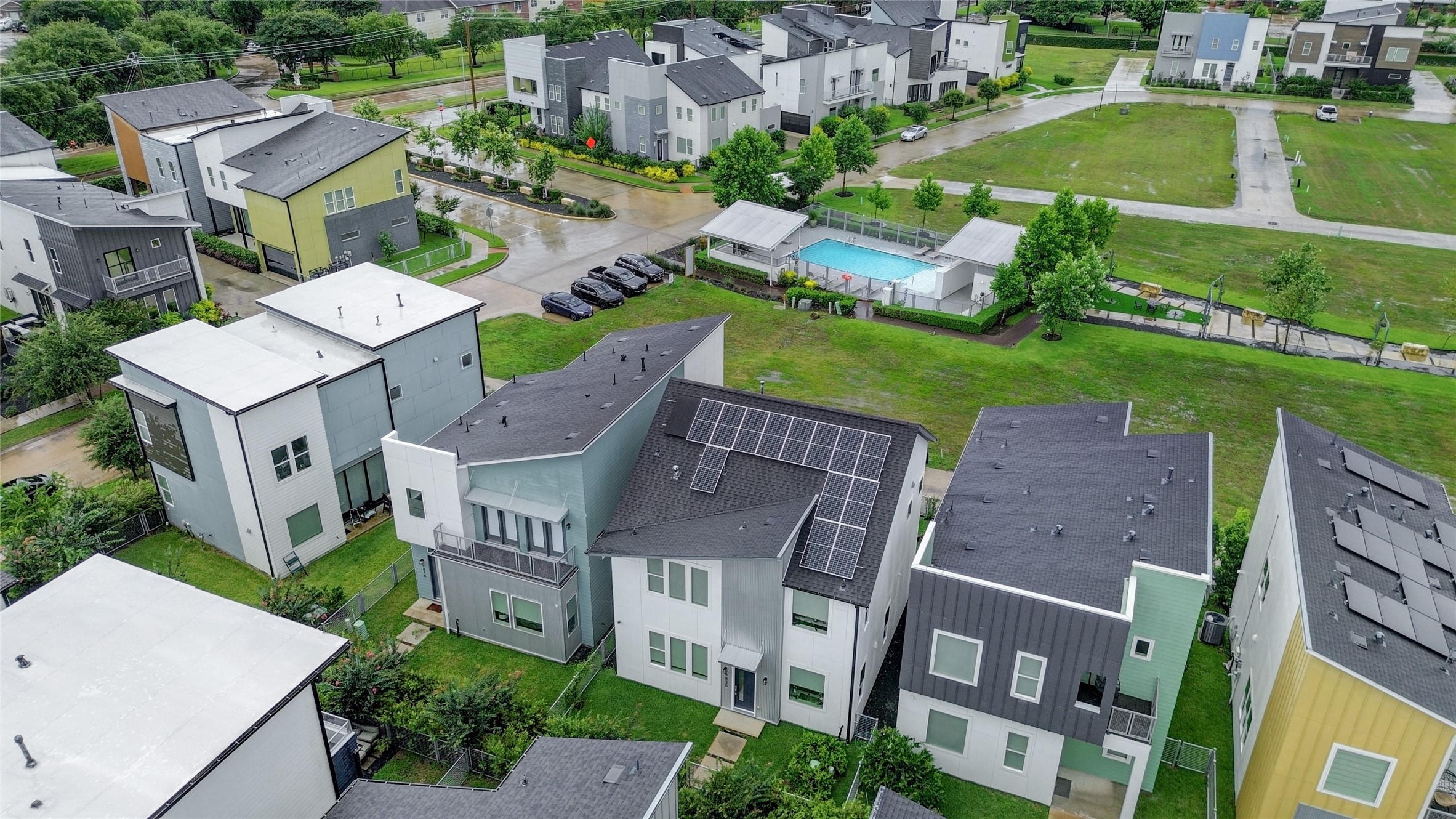 Modern, eco-friendly homes with sleek designs and solar panels, set in a community featuring a private pool and lush green spaces.