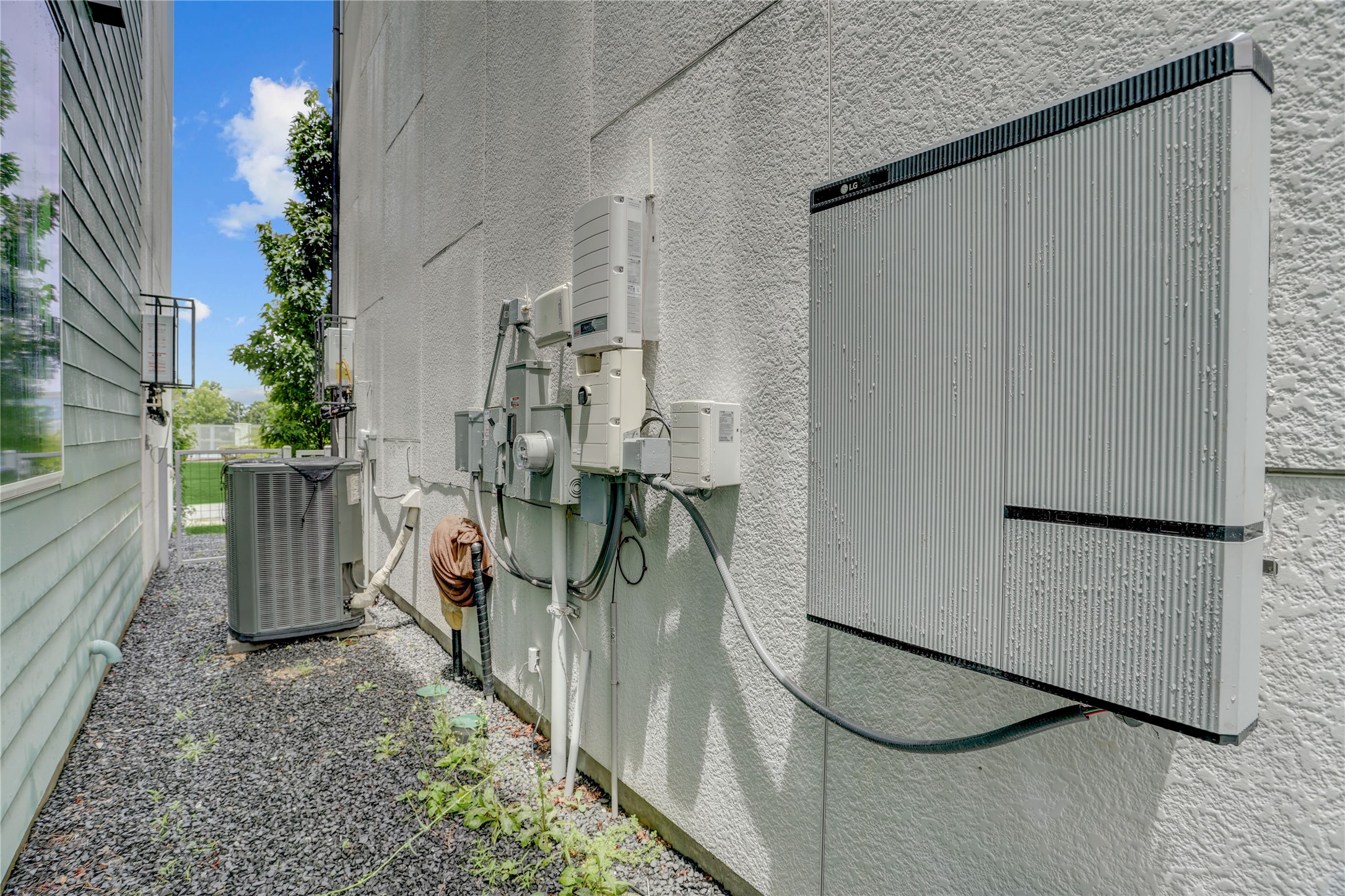 The battery backup system is shown along with the Neatly organized utilities and an efficient air conditioning unit enhance this home's exterior functionality.