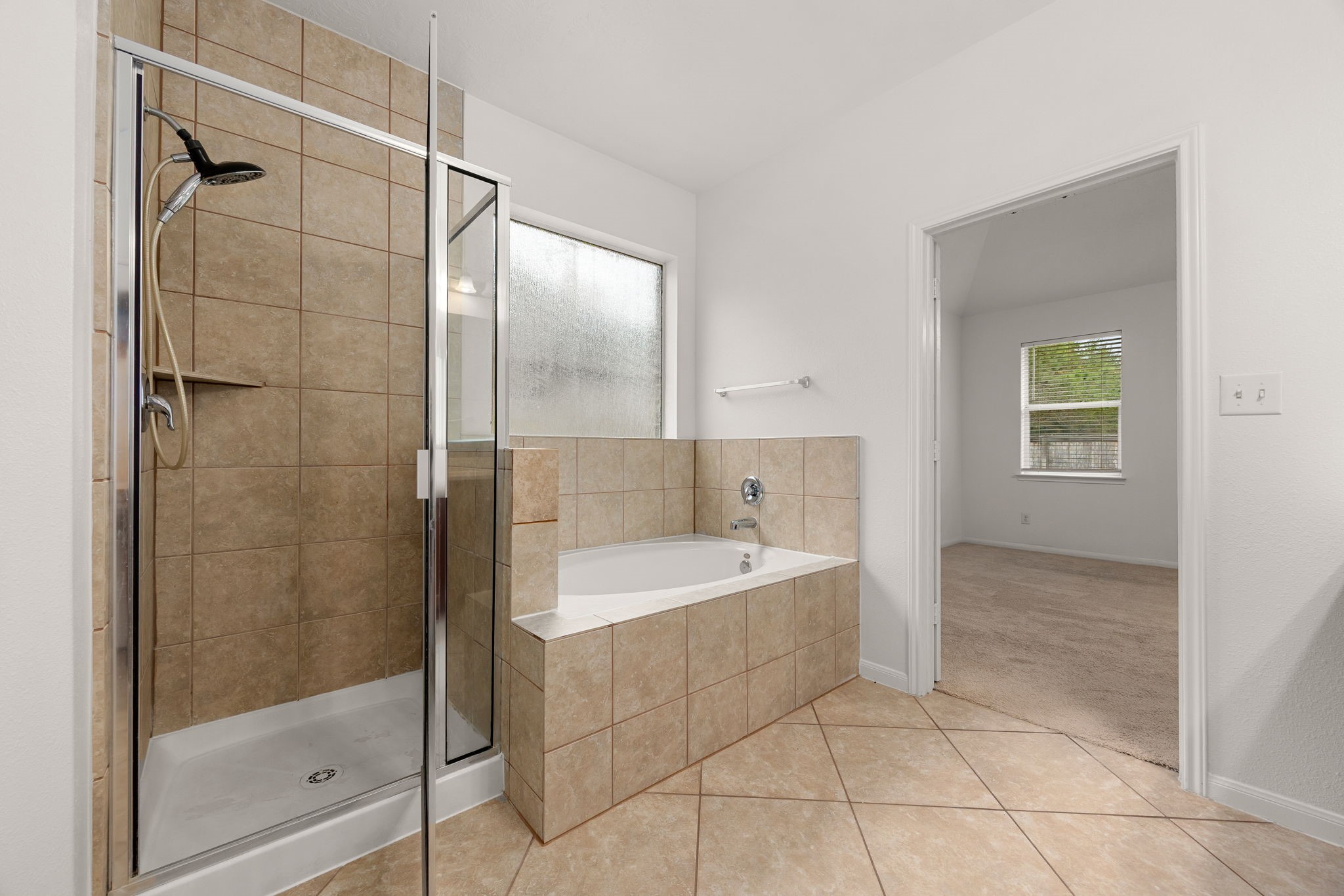 Unwind in the tile-surround soaking tub beneath a frosted privacy window, or step into the separate glass-enclosed shower with a handheld showerhead.