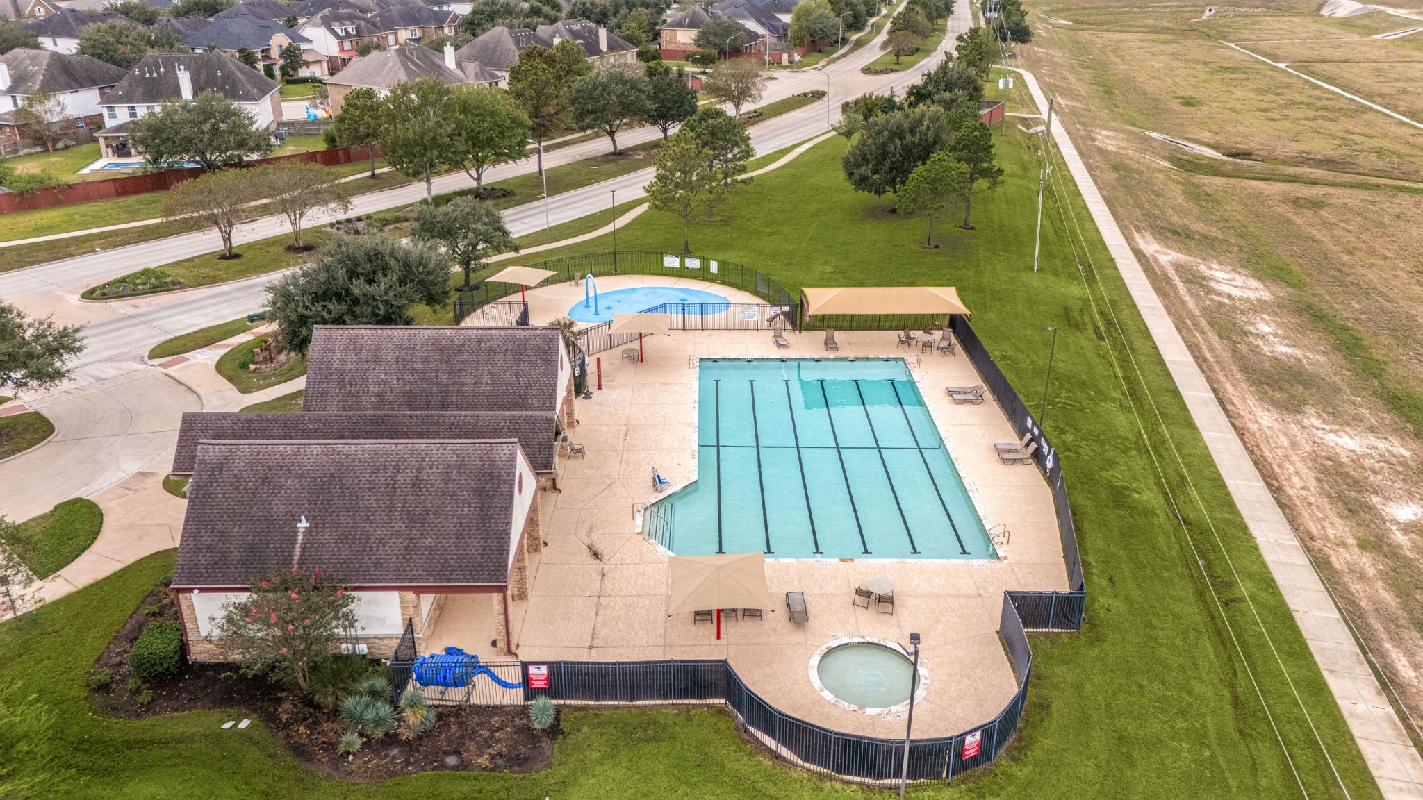 The Silver Ranch recreation center features a six-lane swimming pool, separate splash pad, and shaded poolside seating. A paved walking trail extends alongside the amenity area and through the surrounding community.