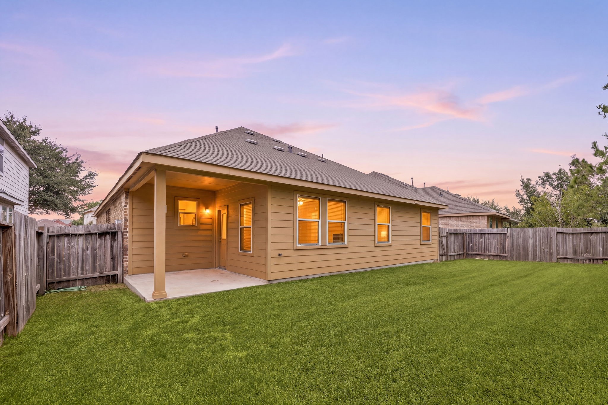 As evening falls, the covered patio opens onto a fully fenced backyard with a wide, level lawn. Its an inviting setting for outdoor dining and relaxing.