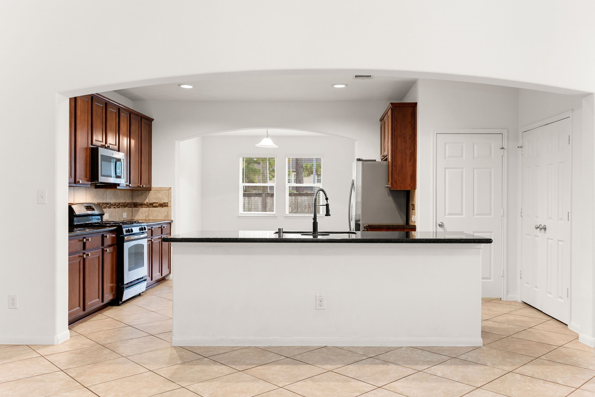 A sweeping arched opening frames the kitchen, where a large granite-topped island with a breakfast bar takes center stage and convenient pantry storage sits just steps away. A sweeping arched opening frames the kitchen, where a large granite-topped island with a breakfast bar takes center stage and convenient pantry storage sits just steps away.