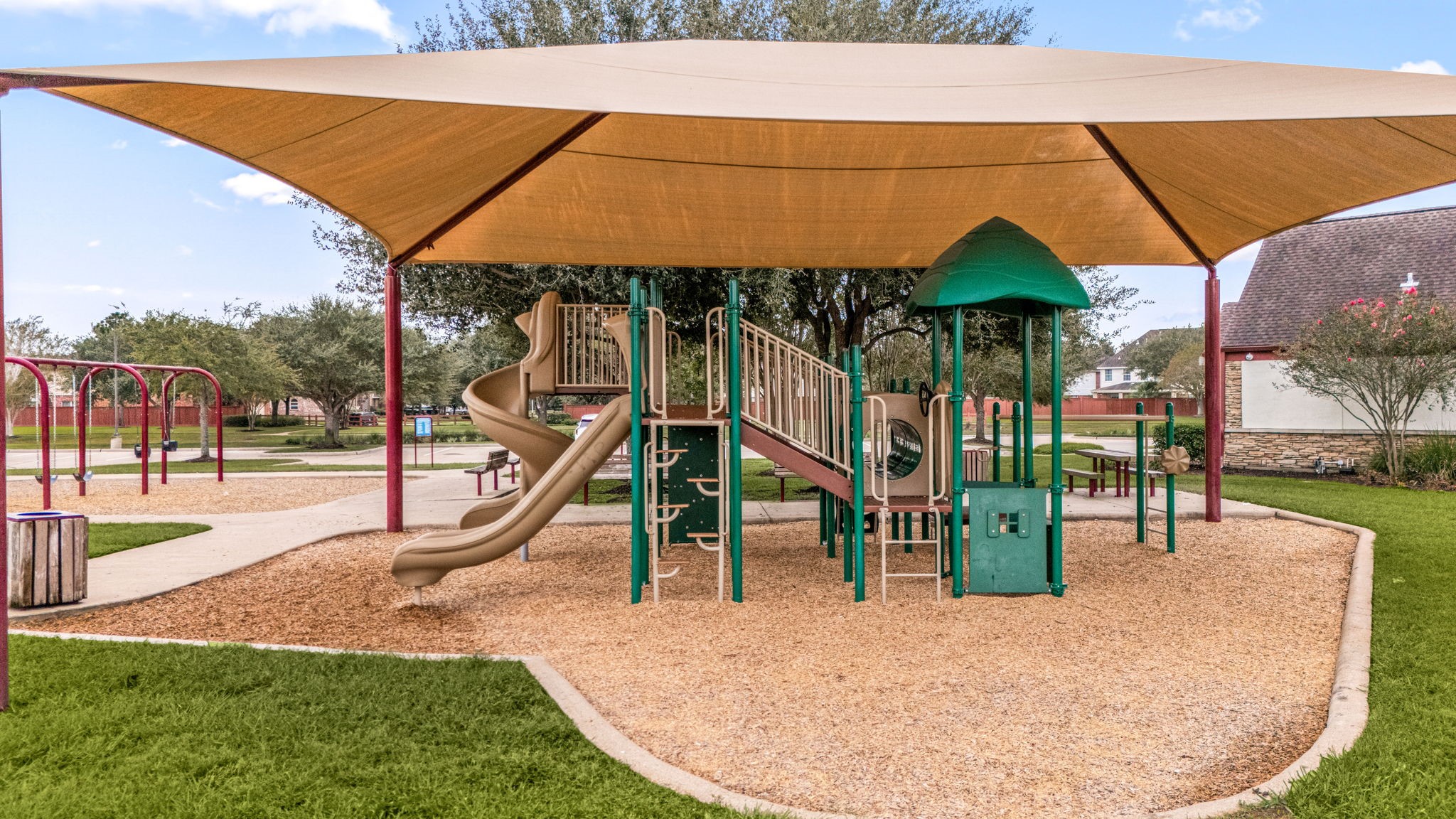 Silver Ranchs neighborhood playground includes slides, climbing features, swings, and picnic tables for outdoor recreation. A large shade canopy covers the main play structure, providing added protection from the Texas sun.