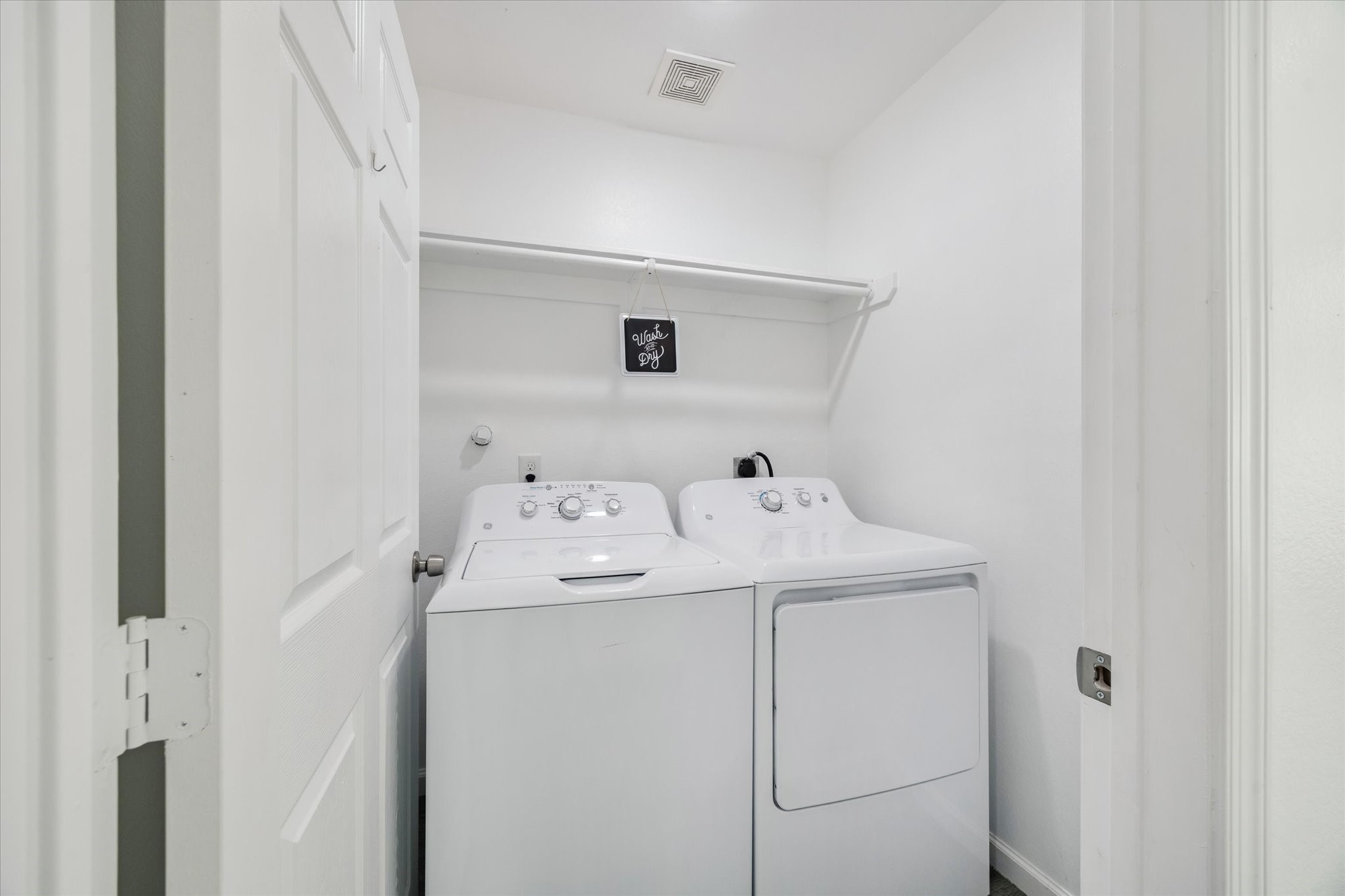 A dedicated laundry room includes overhead shelving for convenient storage. Easily accessible to every bedroom, this utility room adds everyday functionality to the home.