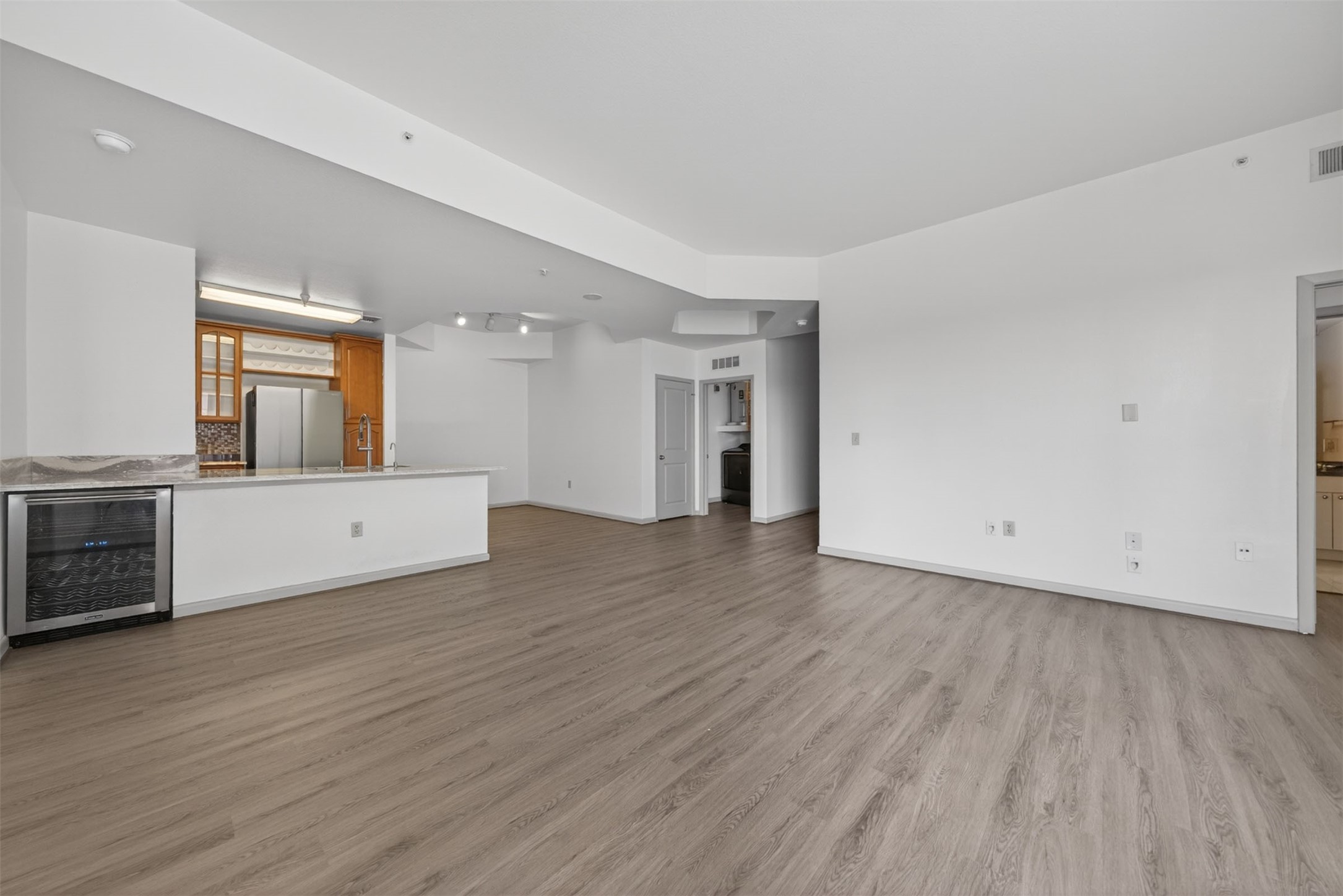 Spacious open-concept living area featuring modern luxury vinyl plank flooring, a sleek kitchen with stainless steel appliances, and ample natural light. Spacious open-concept living area featuring modern luxury vinyl plank flooring, a sleek kitchen with stainless steel appliances, and ample natural light.