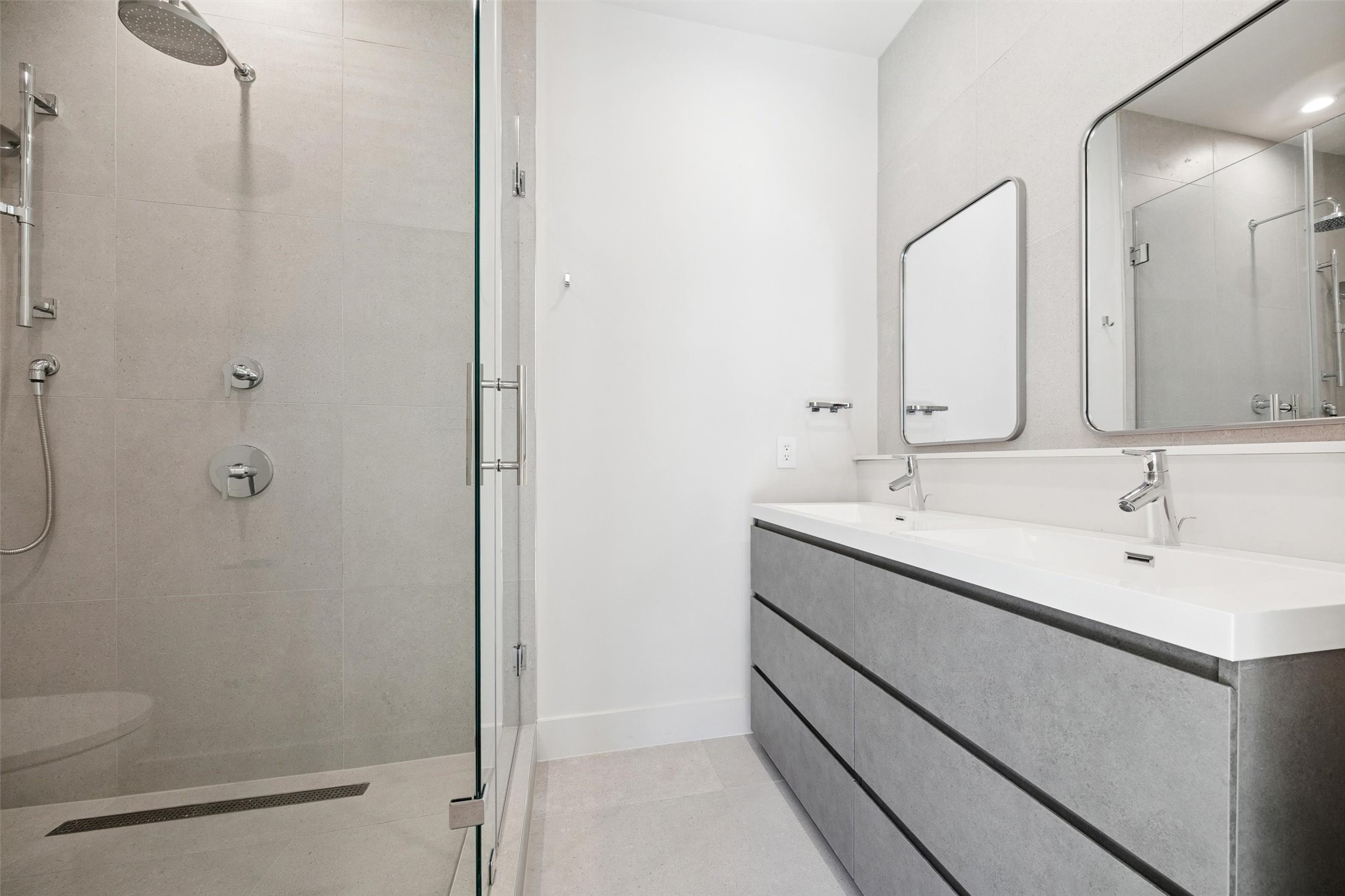 Primary bathroom with large glass surround shower and double sinks.