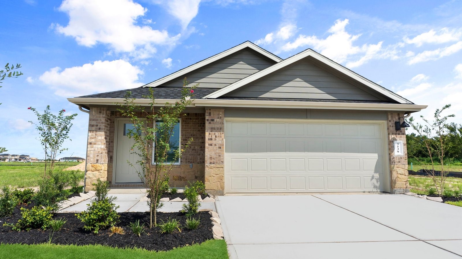 Newly built single story home with traditional architecture, a garage, and landscaped front yard.