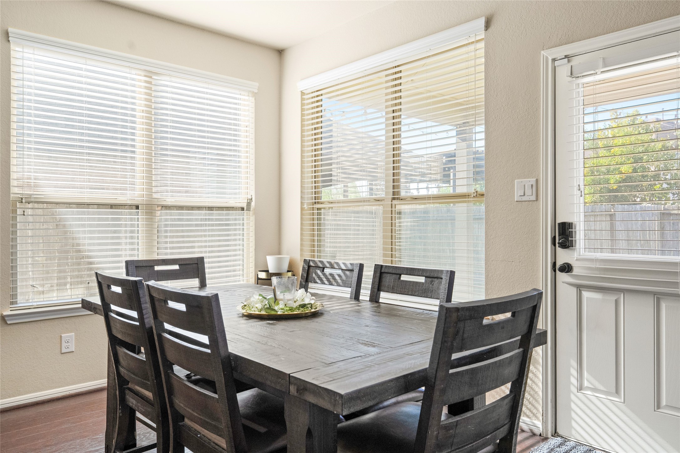 Bright dining area featuring large windows and a charming wooden table, perfect for family gatherings.
