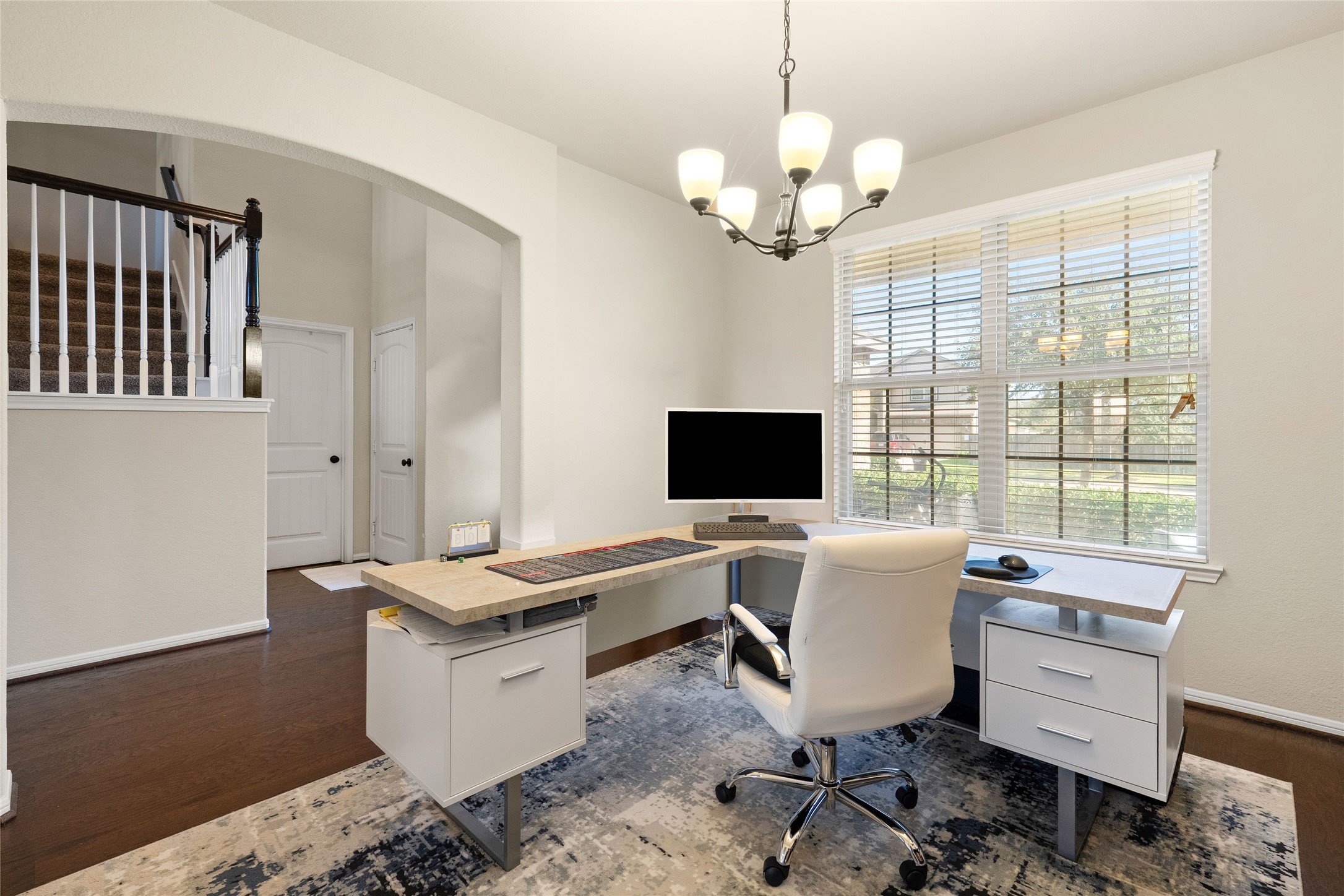 Bright and inviting home office featuring sleek modern furniture, a large window for natural light, and elegant lighting fixtures, perfect for productivity and comfort.