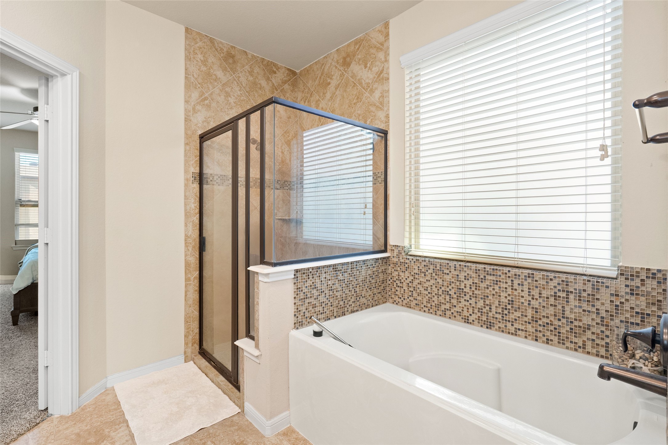 Elegant bathroom featuring a luxurious soaking tub and a spacious glass-enclosed shower, complemented by stylish tile accents and abundant natural light.