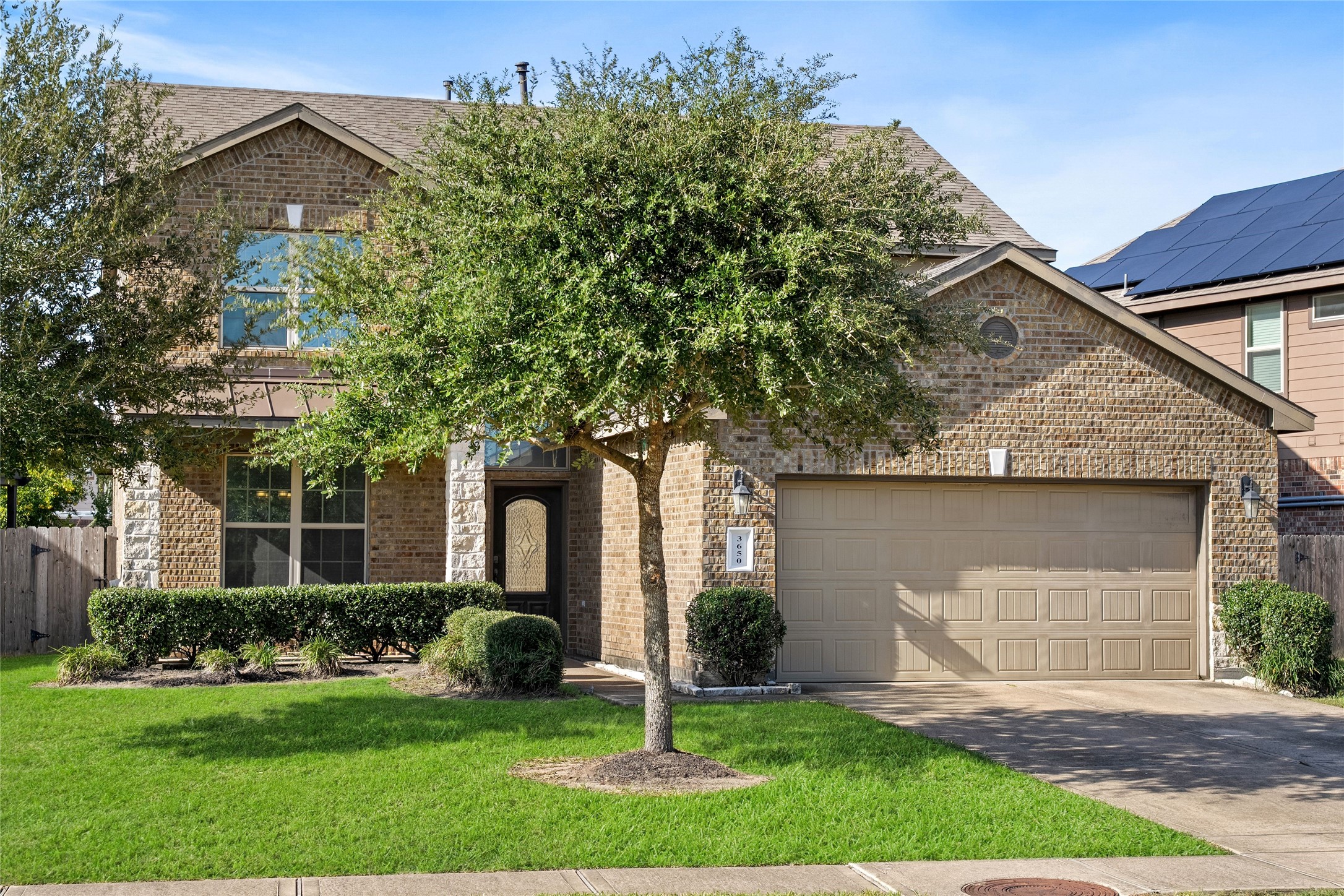 Charming two-story brick home with a well-maintained front yard, mature tree, and spacious two-car garage.