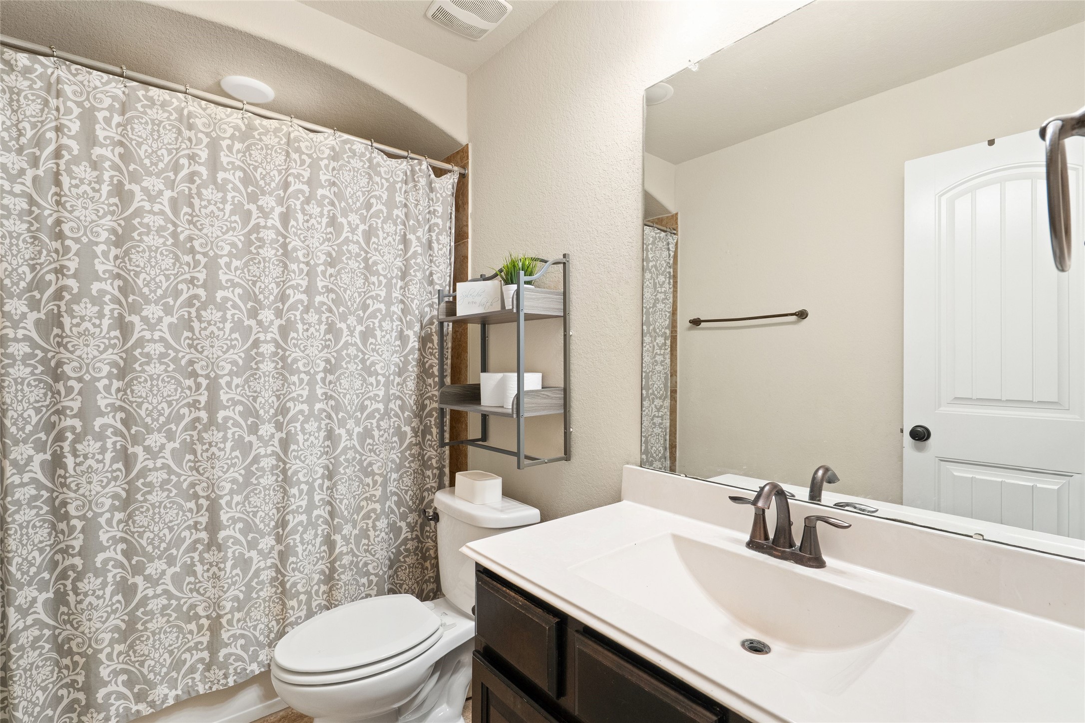 Charming bathroom with elegant patterned shower curtain, sleek fixtures, and ample storage, offering a cozy and functional space.