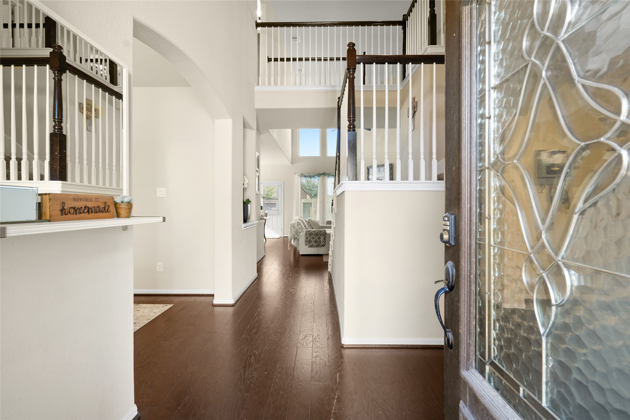 Inviting two-story foyer with elegant wood flooring leads to an open living space filled with natural light.