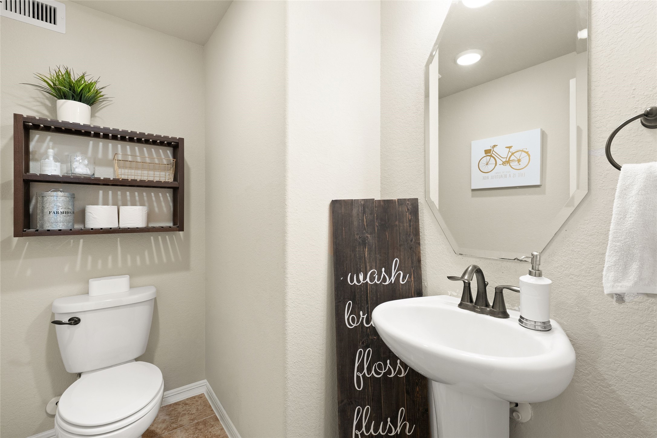 Charming half-bathroom with a modern pedestal sink, elegant fixtures, and stylish shelving for storage.