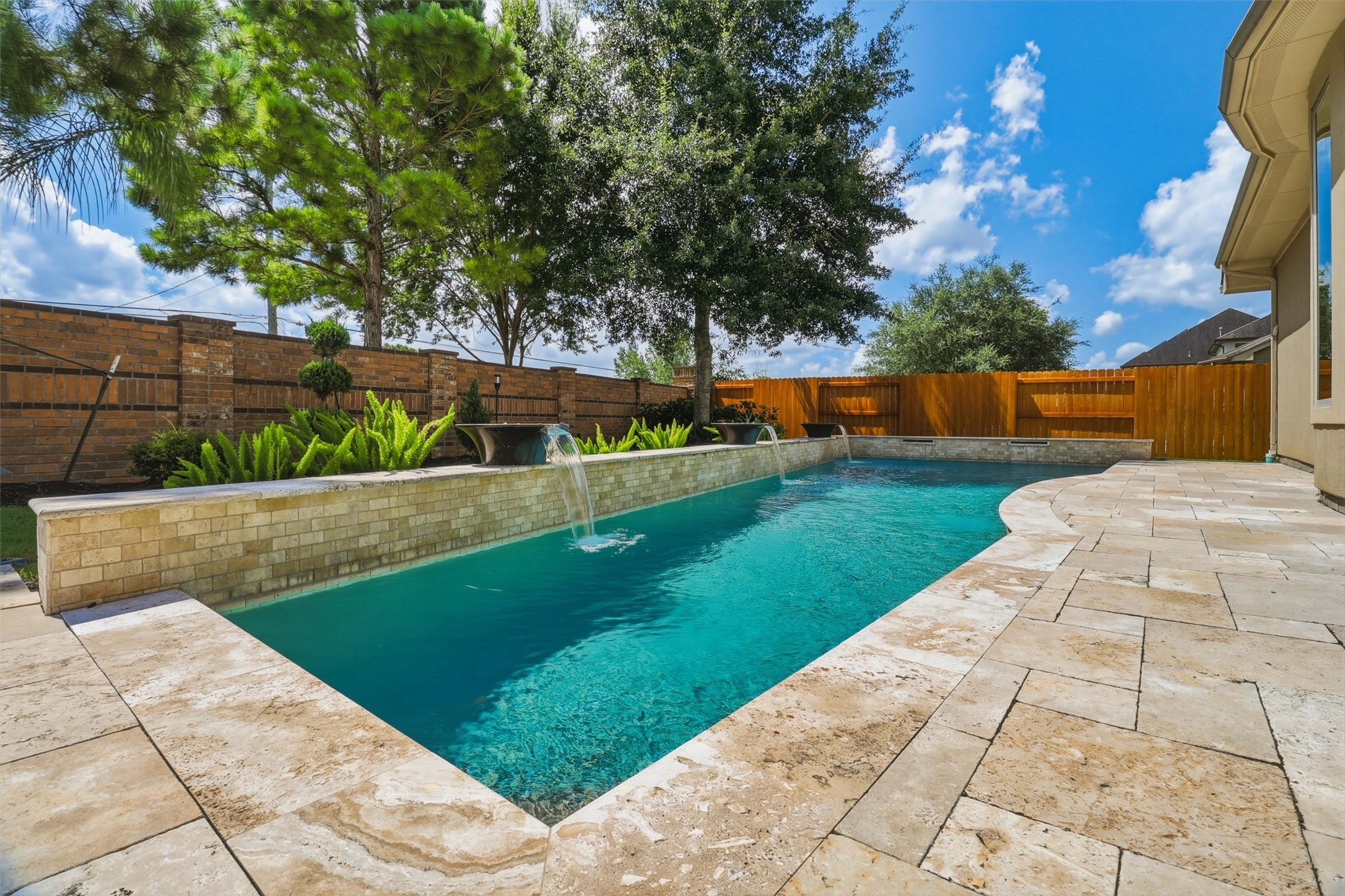 Gorgeous travertine decking surrounds the classic pool with three water bowl features and two shears at the far end of the pool. This is a low maintenance yard, yet still provides plenty of spaces for relaxing and entertaining! Gorgeous travertine decking surrounds the classic pool with three water bowl features and two shears at the far end of the pool. This is a low maintenance yard, yet still provides plenty of spaces for relaxing and entertaining!