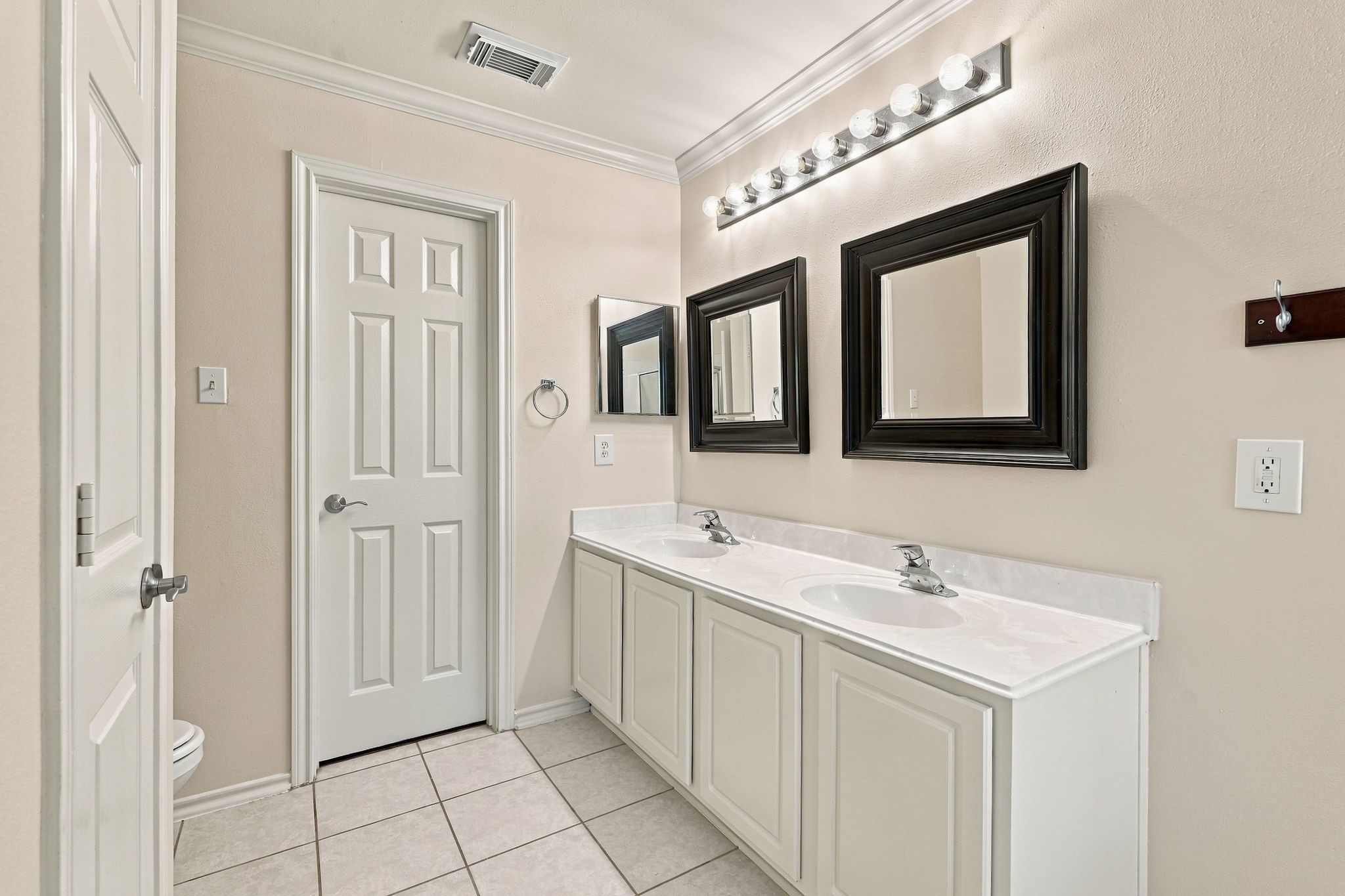 The primary bathroom offers dual sinks, trendy mirrors, and a large walk in closet (behind this door)