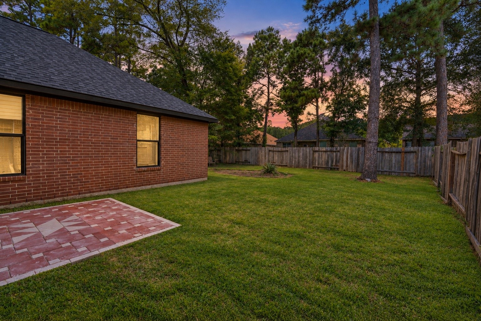 The rear exterior of 18 Griffin Hill Court is a private outdoor sanctuary, surrounded by mature trees and established landscaping that provide natural shade and excellent privacy. The well-maintained brick facade continues beautifully along the back of the home, while the spacious backyard offers wonderful potential for outdoor living and recreation.