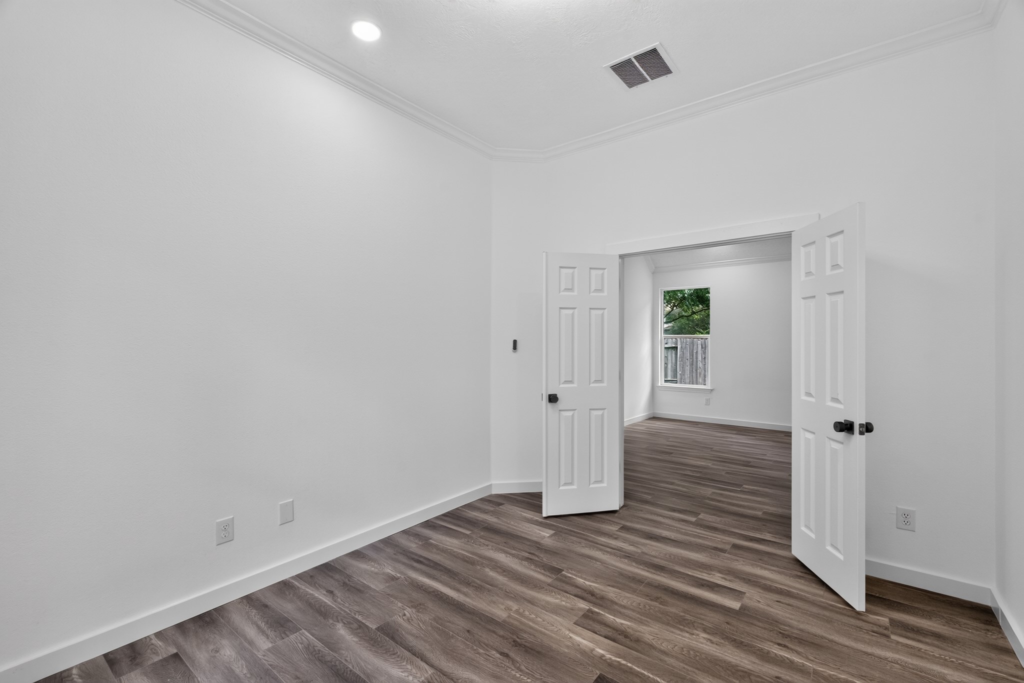 A well-proportioned secondary bedroom at 18 Griffin Hill Court offers clean white walls, dark hardwood-style flooring, and easy access to the hallway beyond. This comfortable room provides flexibility for use as a guest room, children's bedroom, or home office  ready to be personalized to perfectly suit your unique lifestyle and needs.